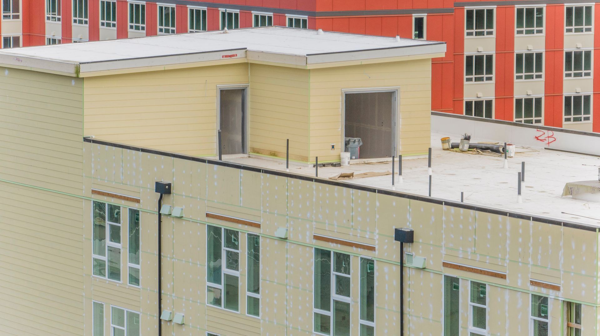 An aerial view of a building under construction with snow on the roof