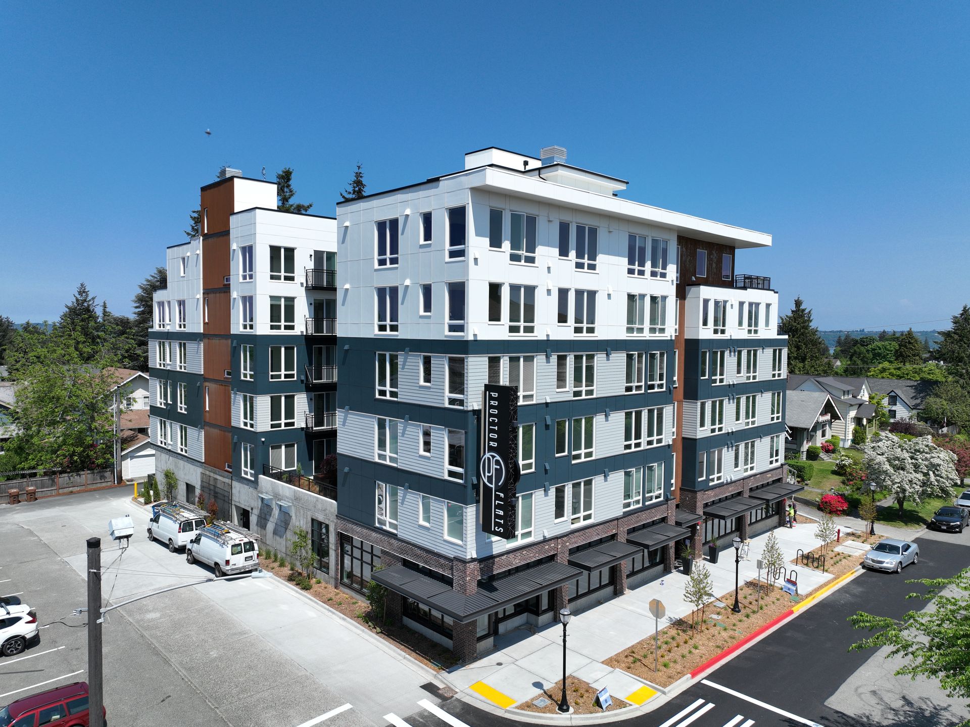 An aerial view of a large apartment building with cars parked in front of it.