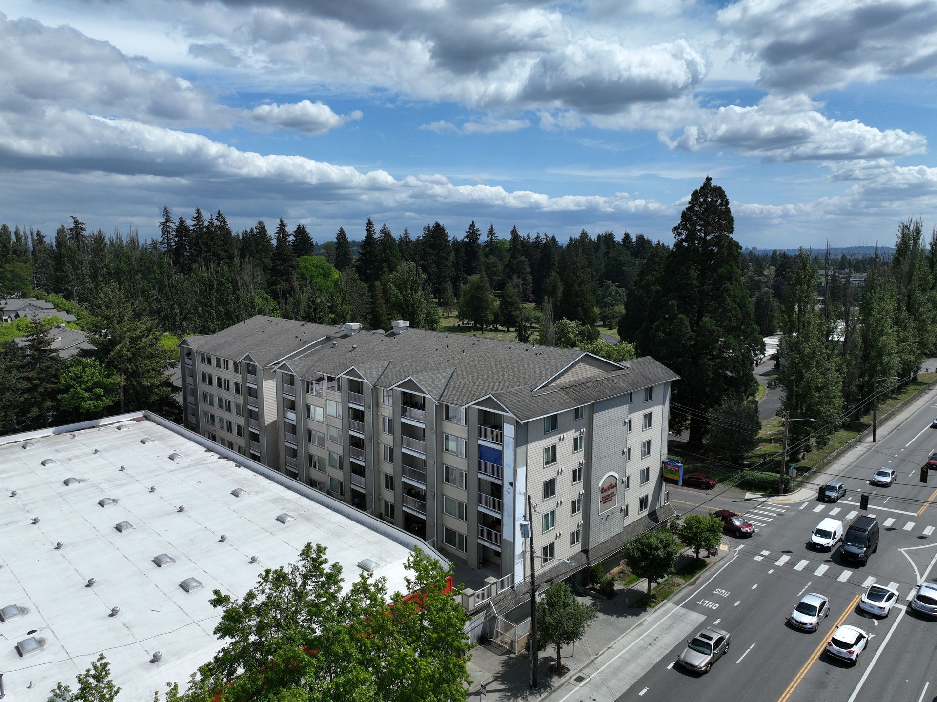 An aerial view of a large apartment building next to a busy street.