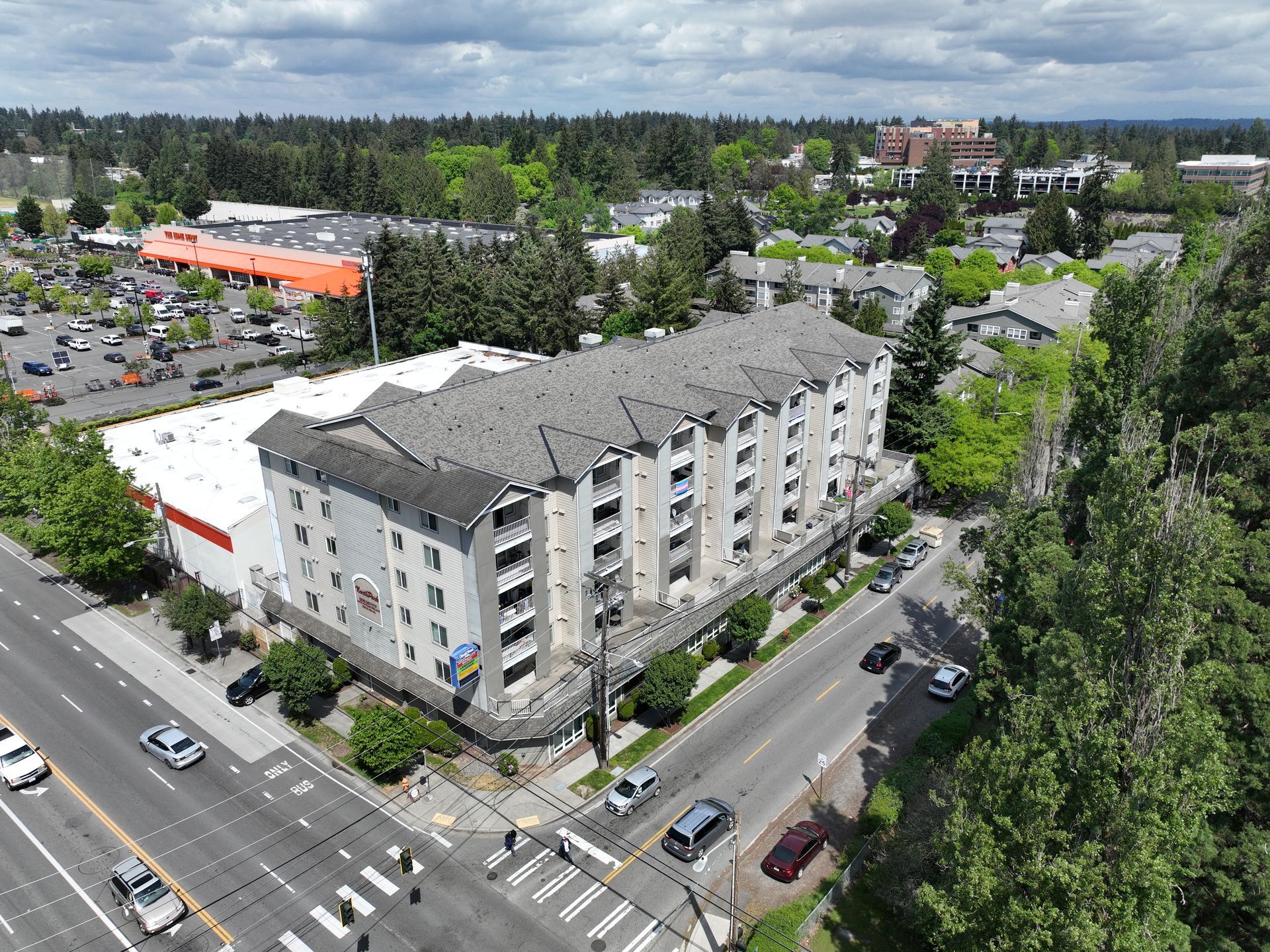 An aerial view of a large apartment building on the corner of a city street.