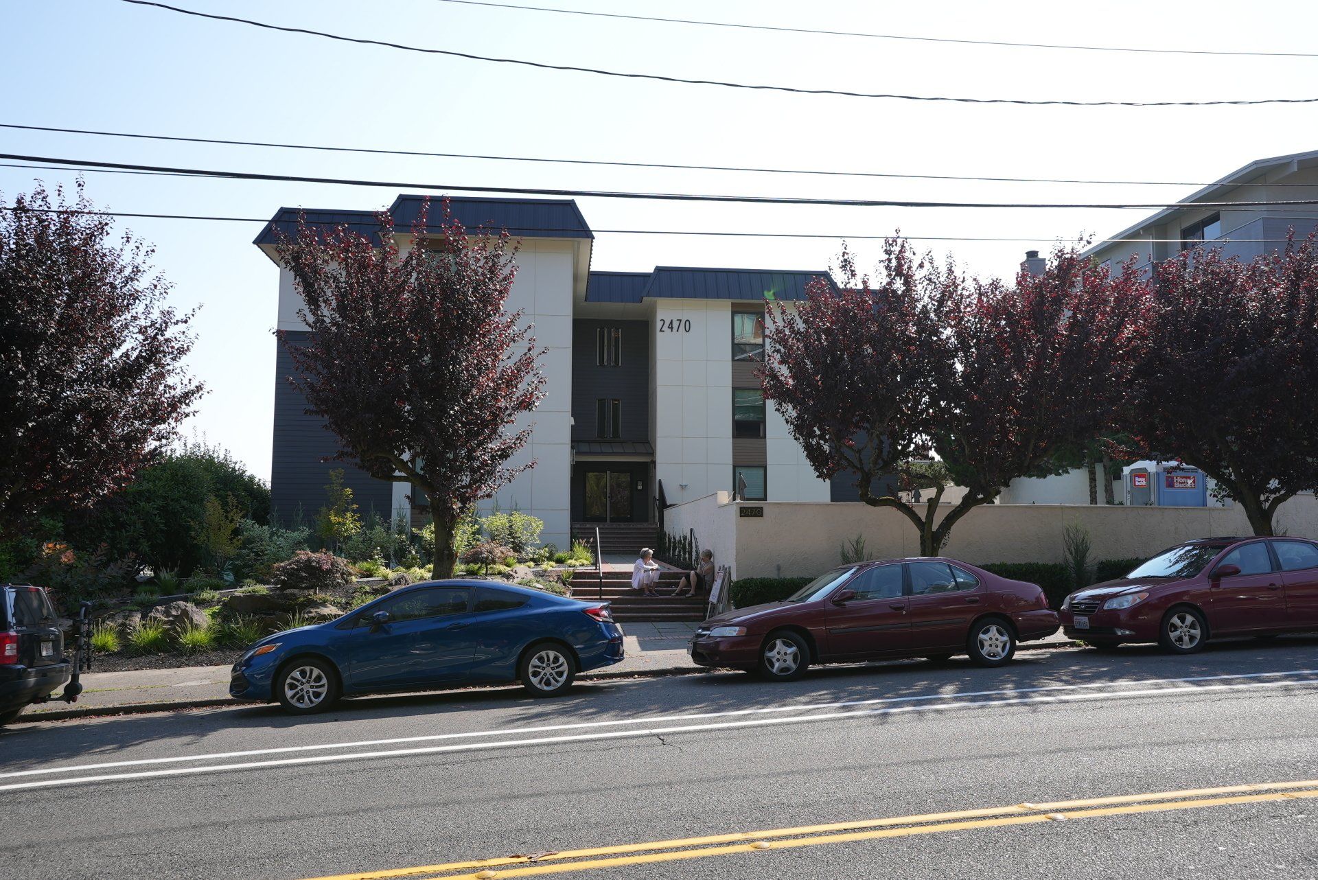 A row of cars are parked in front of a building