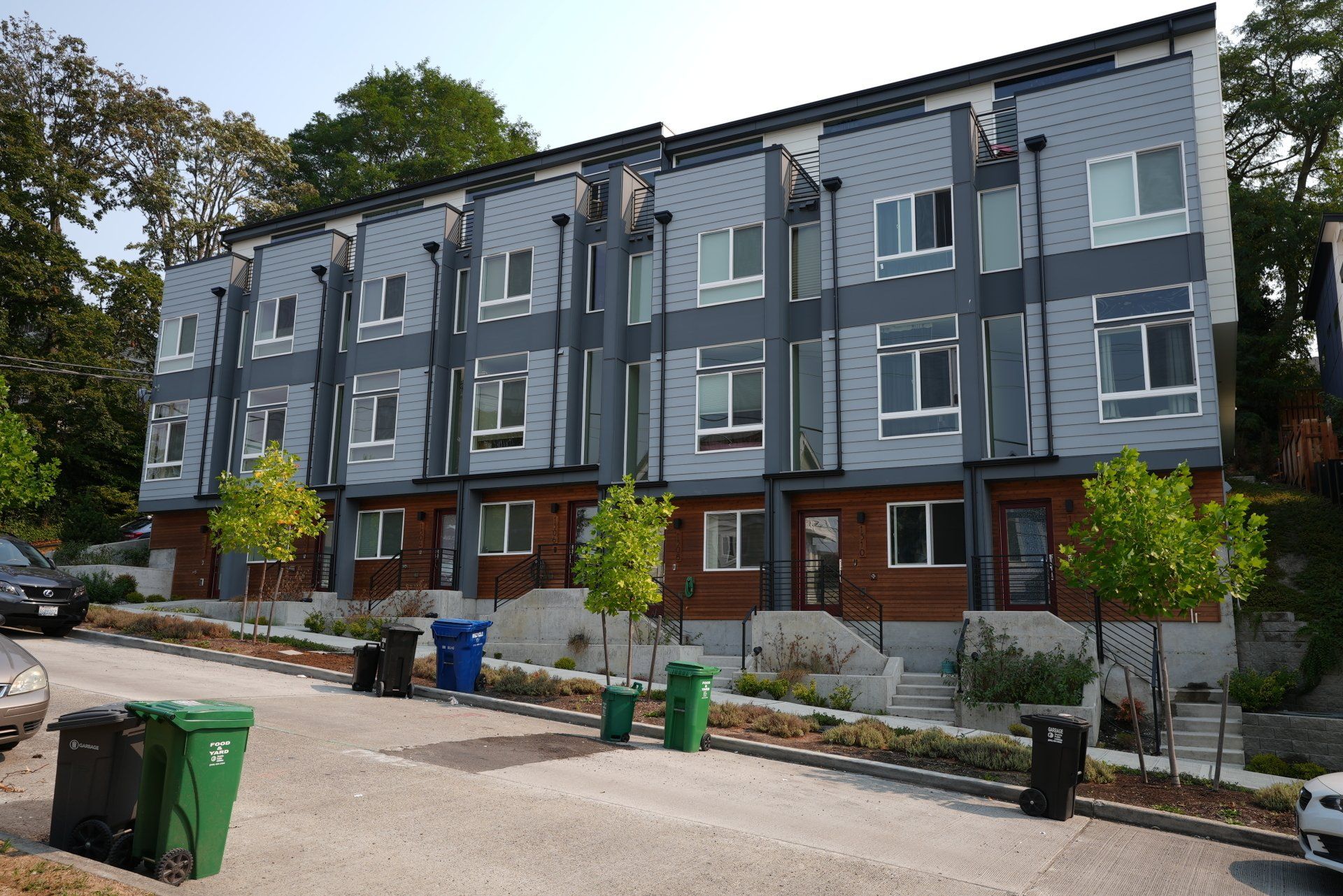 A row of apartment buildings with green trash cans in front of them