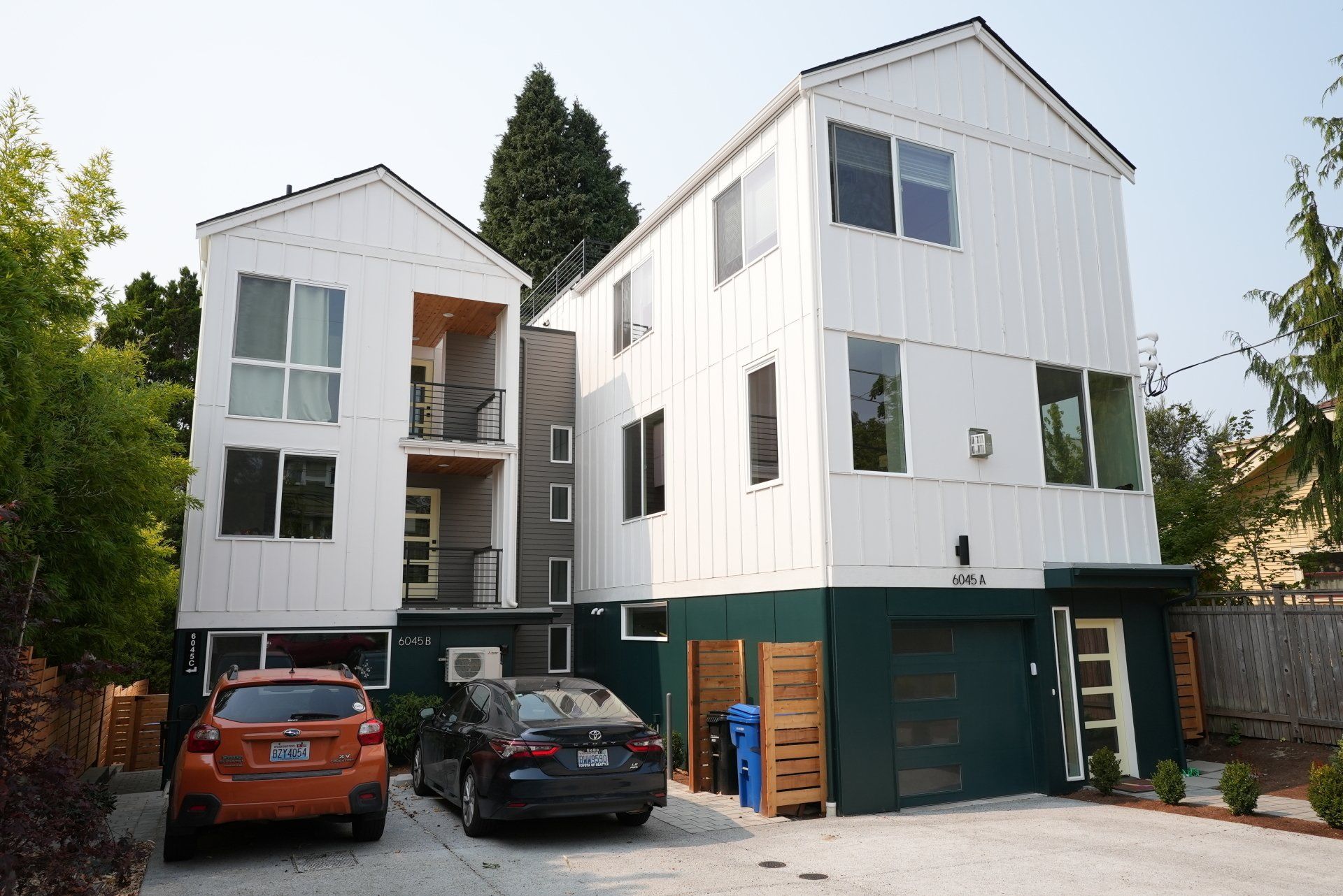 Two cars are parked in front of a white building