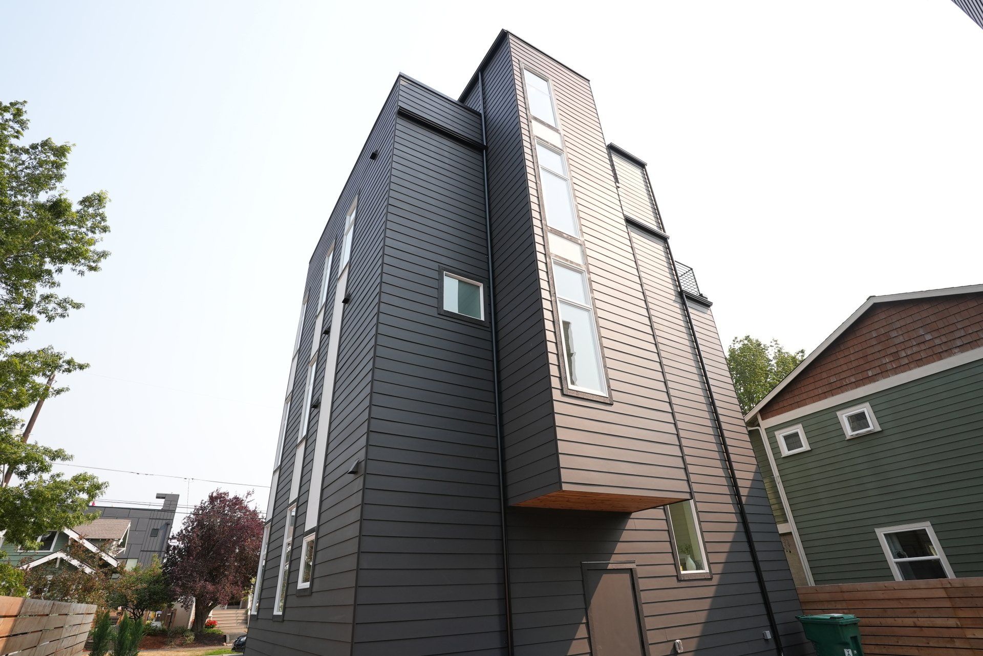 A tall building with a lot of windows and a green house in the background