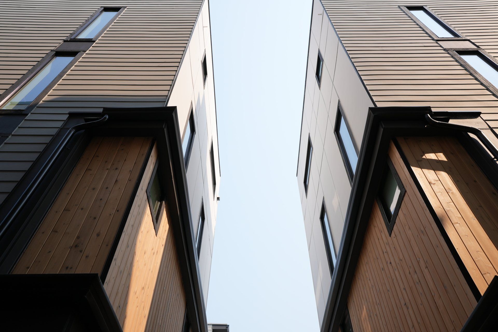 Looking up at two tall buildings with a blue sky in the background