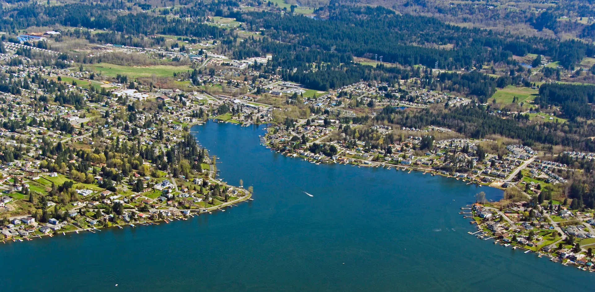 An aerial view of a large body of water surrounded by trees and houses.