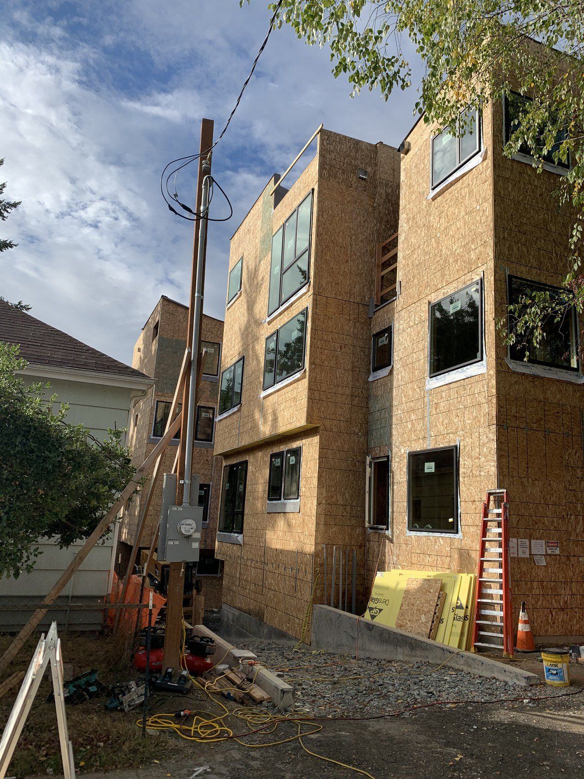 A building under construction with a lot of windows and a ladder in front of it.