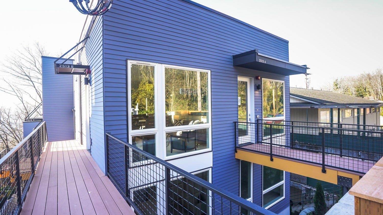 A blue house with a balcony and a wooden deck.