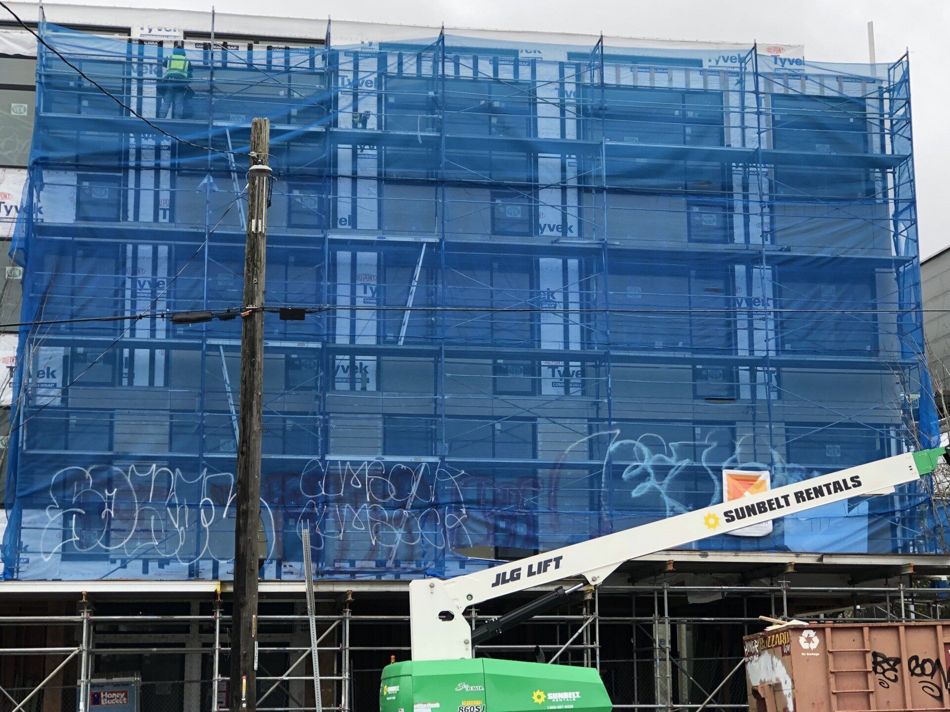 A large building is being built with scaffolding and graffiti on it.