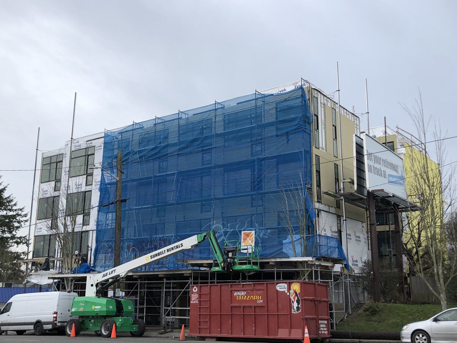 A large building is being remodeled with scaffolding and a crane.