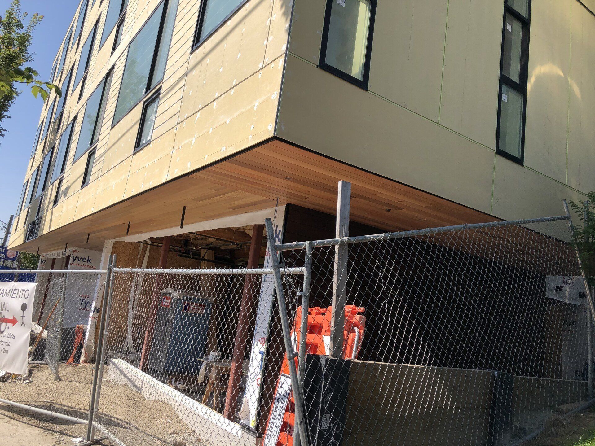 A building under construction is behind a chain link fence.