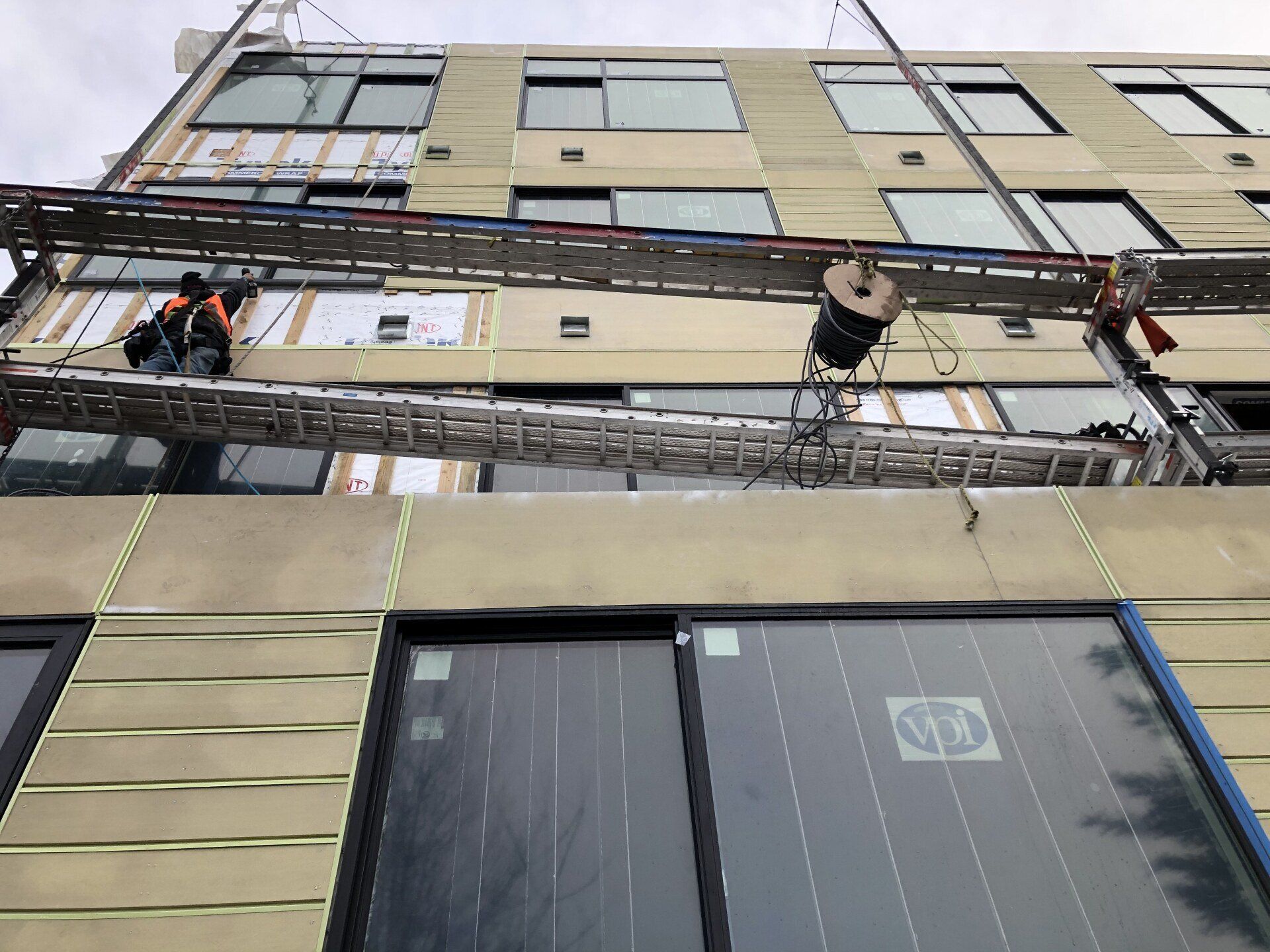 A man is standing on a ladder on the side of a building.