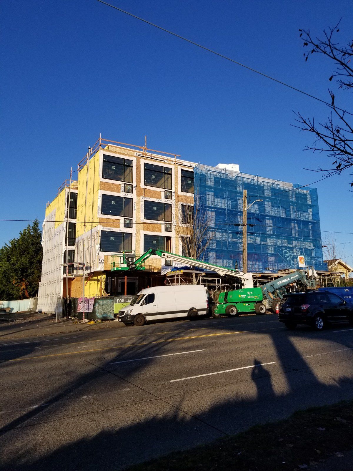 A white van is parked in front of a building under construction.