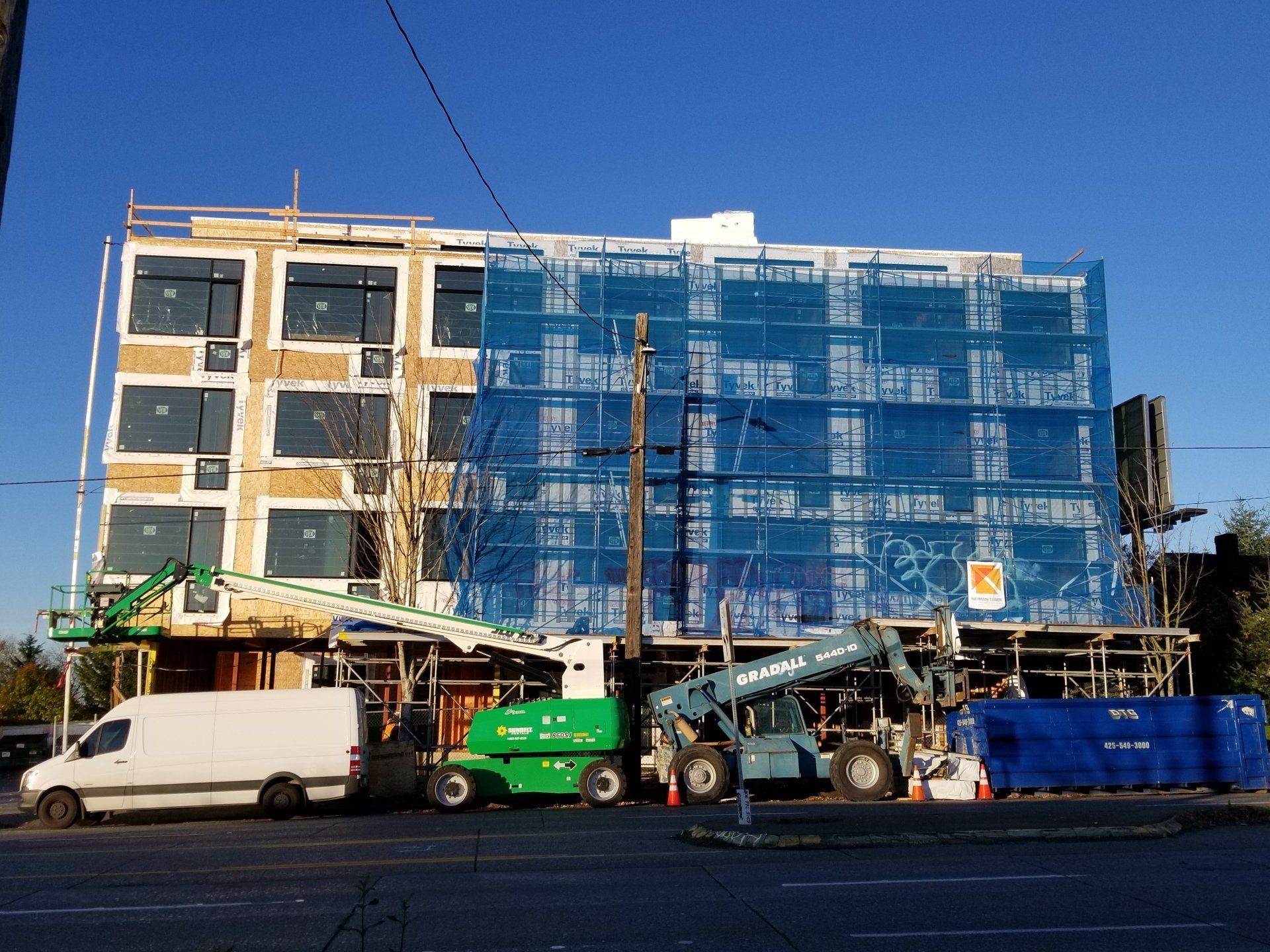 A white van is parked in front of a building under construction