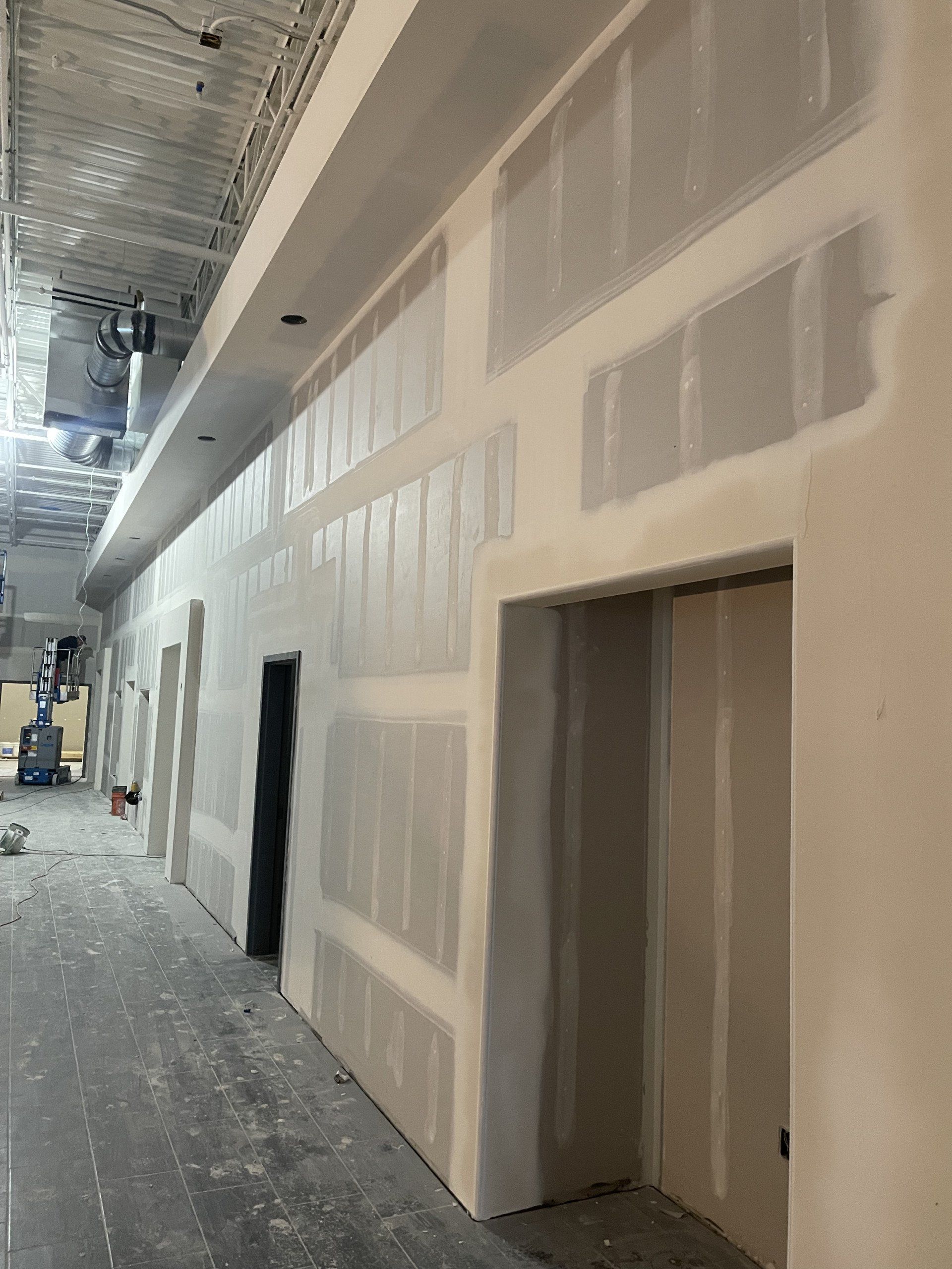 A long hallway with drywall walls and a door.