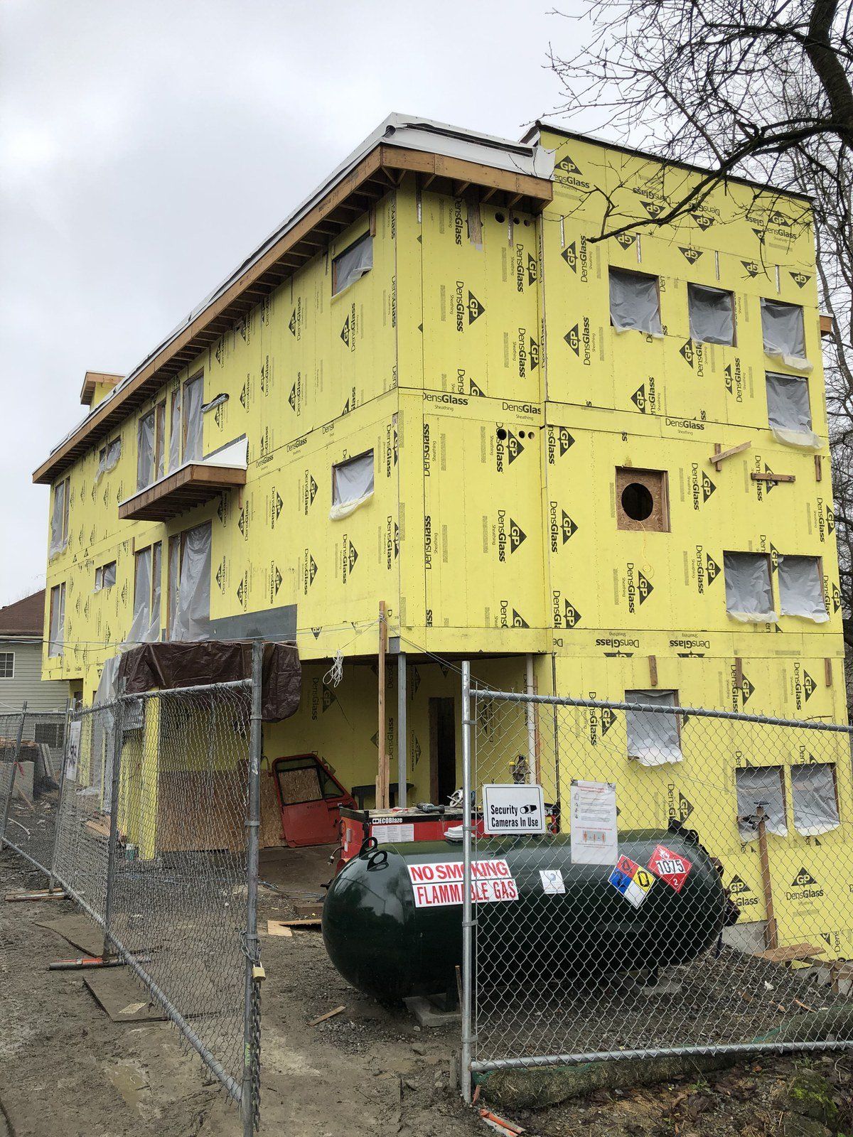 A building under construction with a propane tank in front of it.