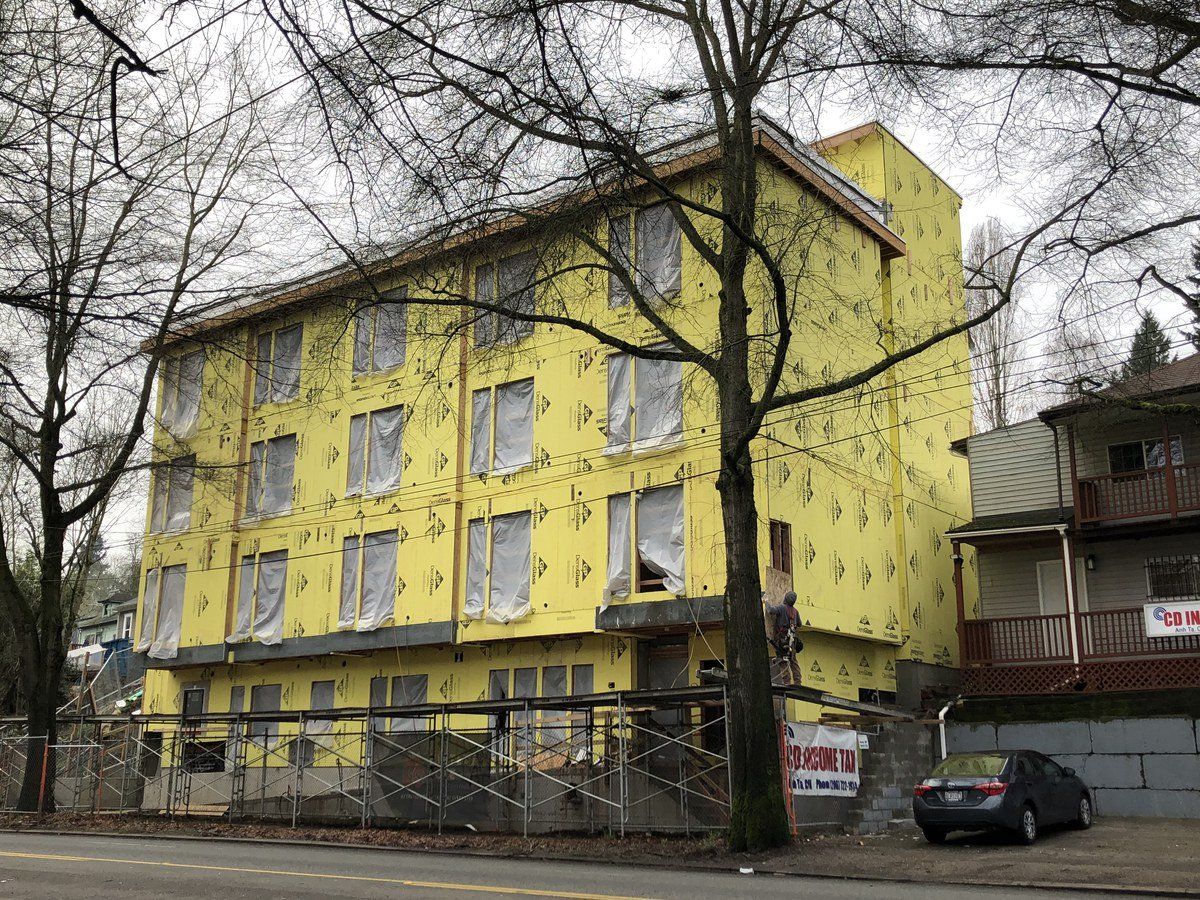 A yellow building with a car parked in front of it is being built.