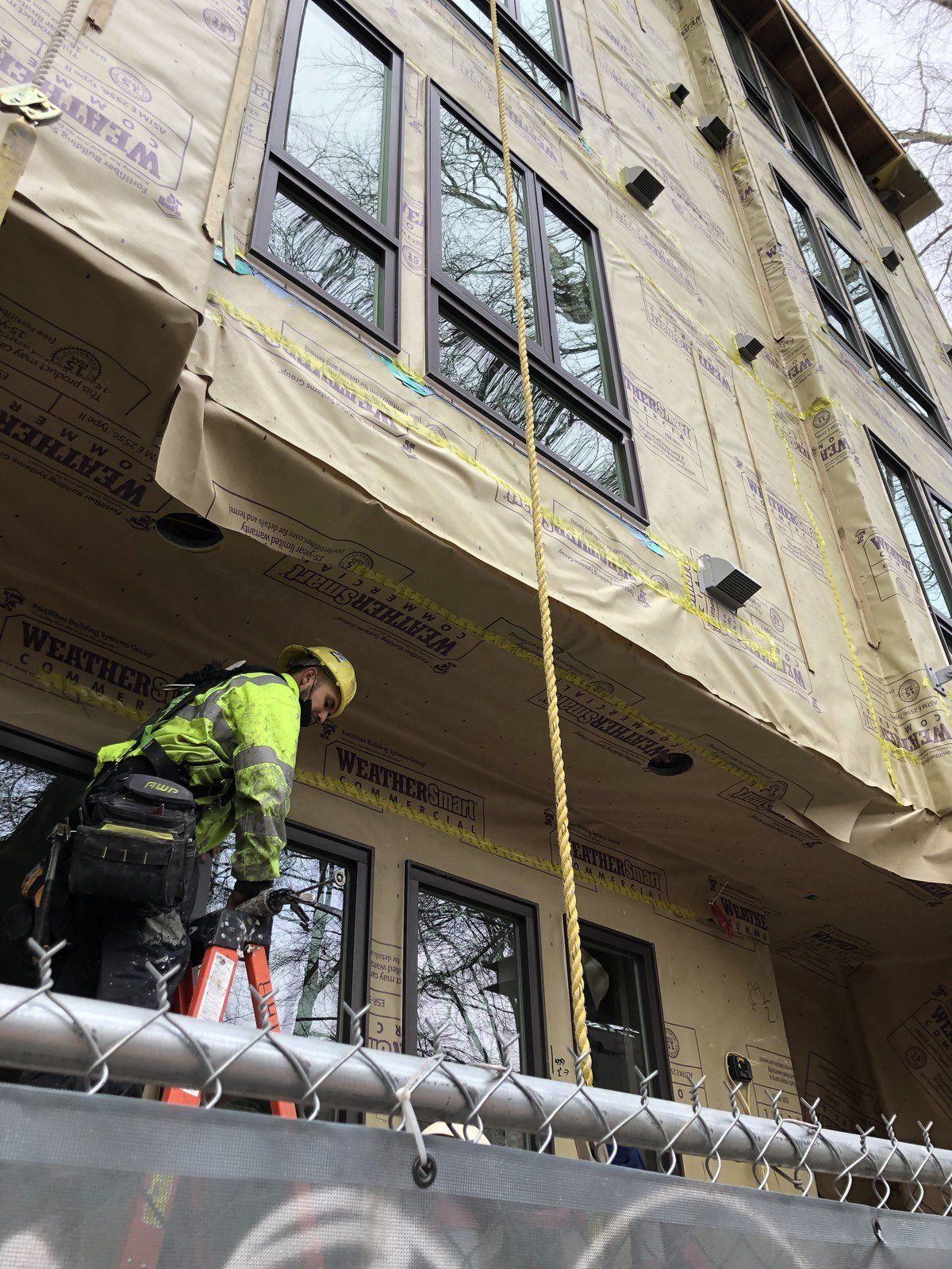 A construction worker is working on the side of a building.