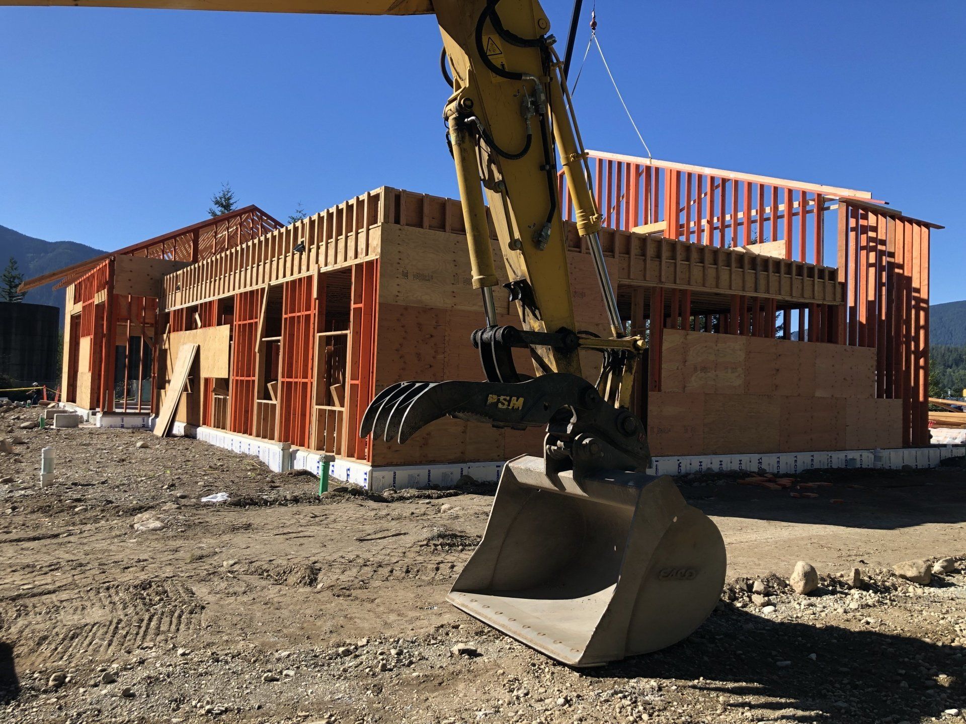 A construction site with a large bucket in front of a building under construction.