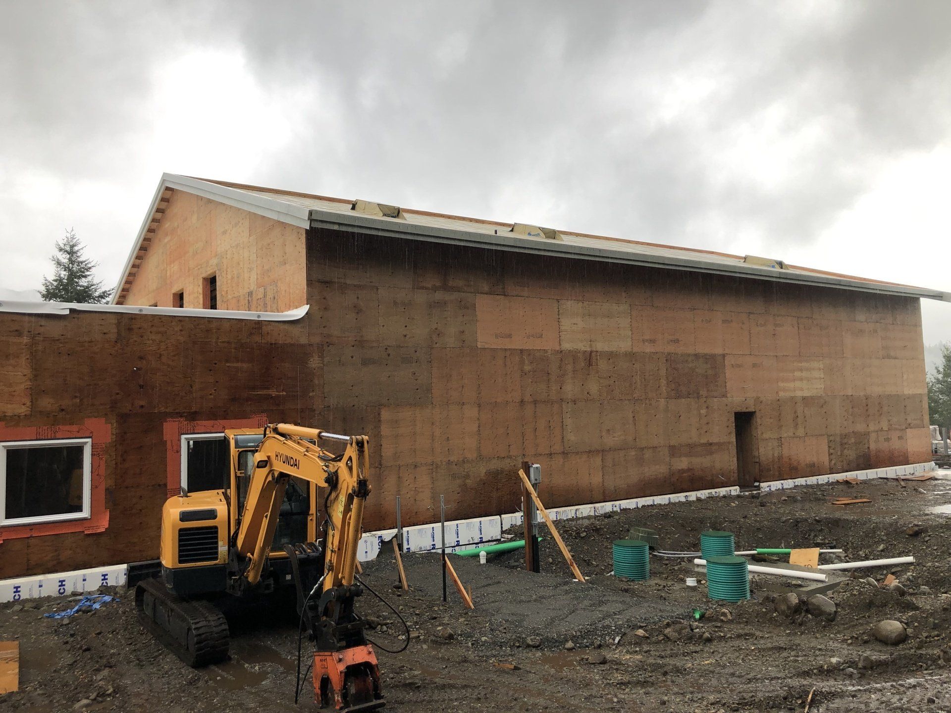 A yellow excavator is parked in front of a building under construction.