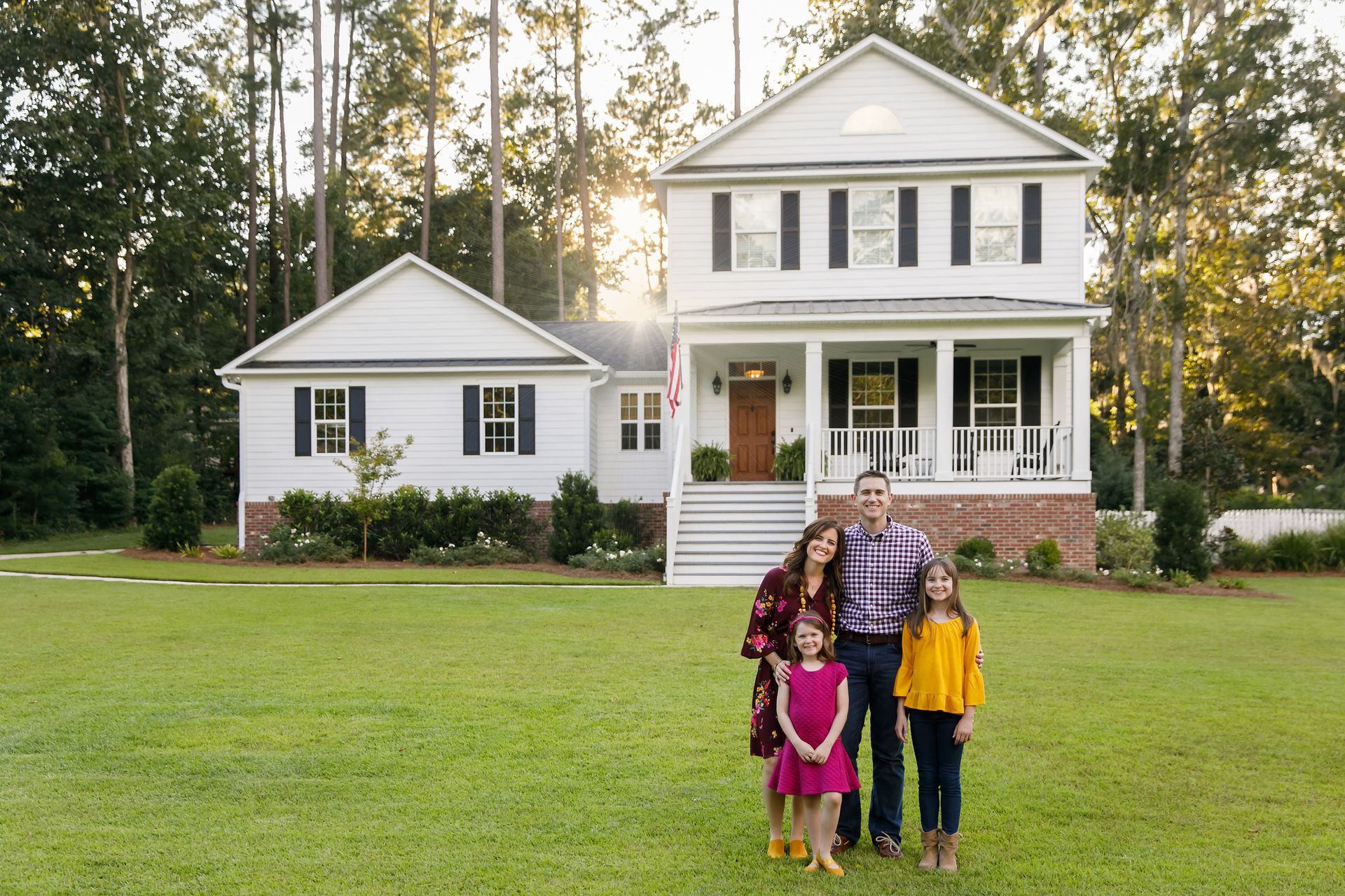 A family is standing in front of a large white house.