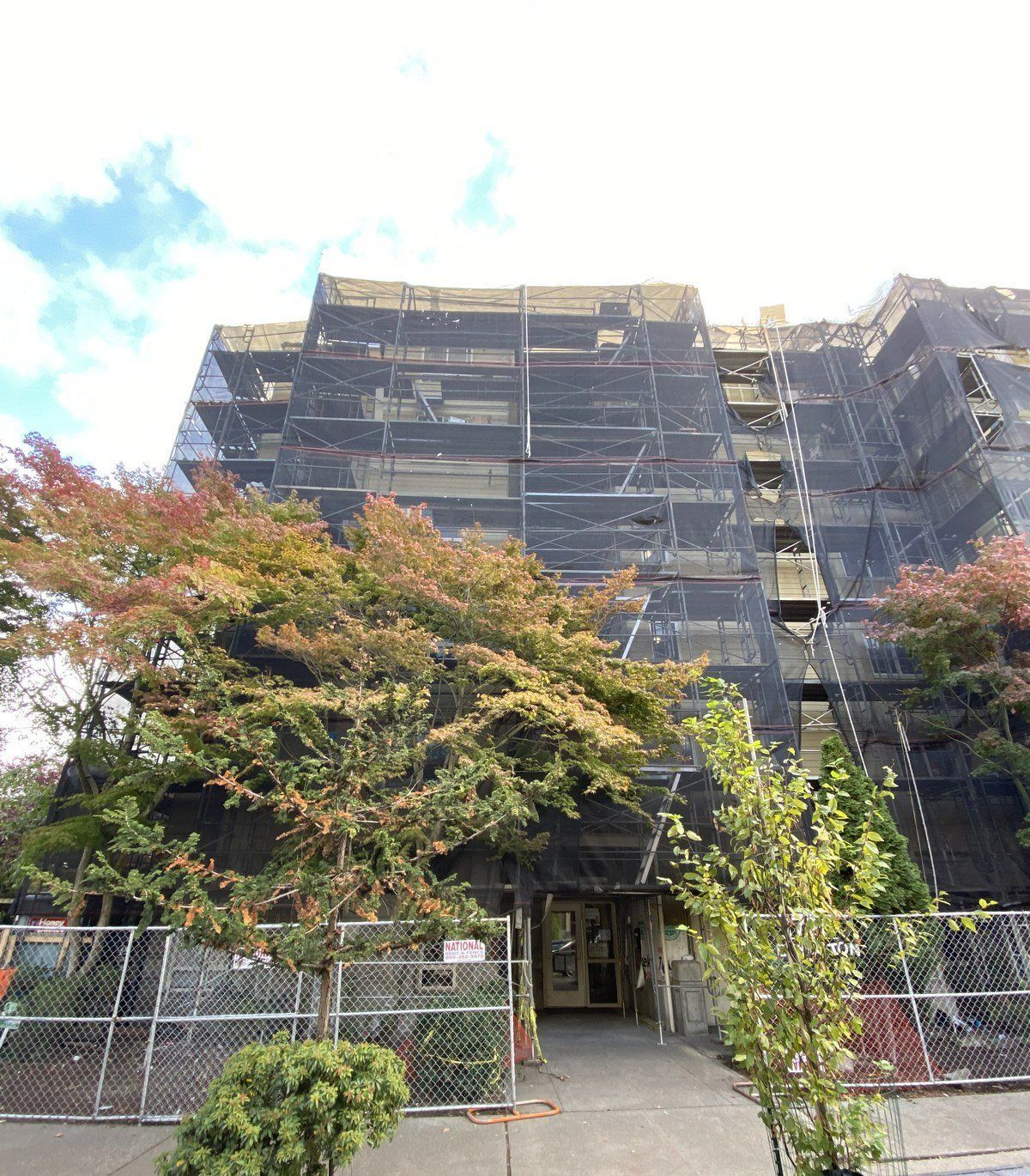 A large building with scaffolding around it and trees in front of it.