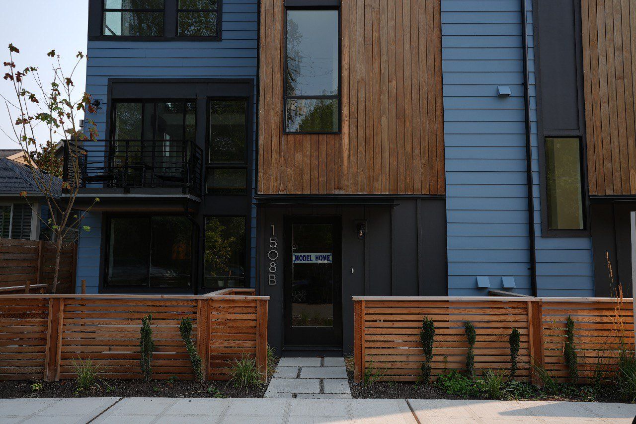 A blue and wooden house with a wooden fence in front of it.