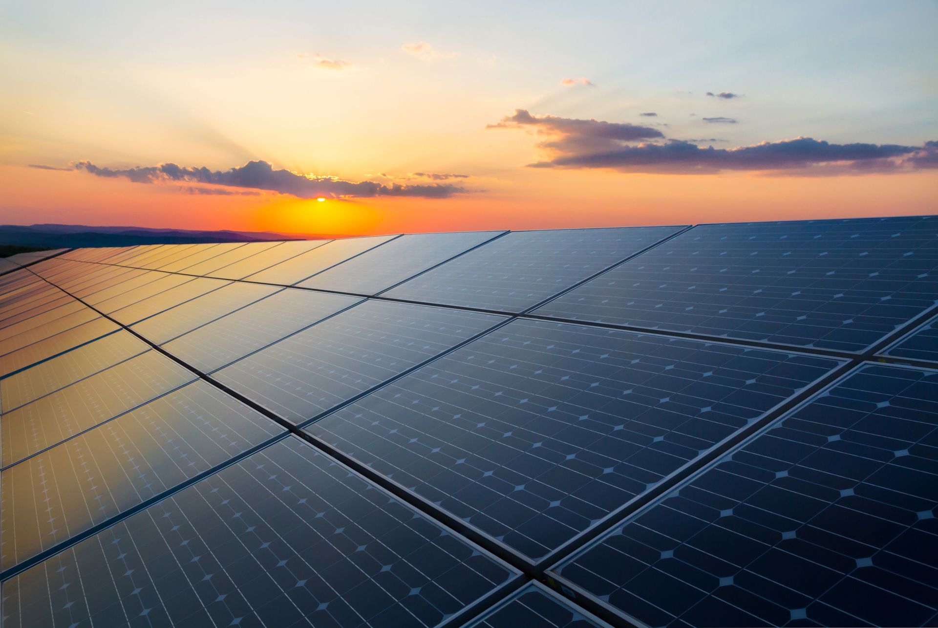 A row of solar panels against a sunset sky