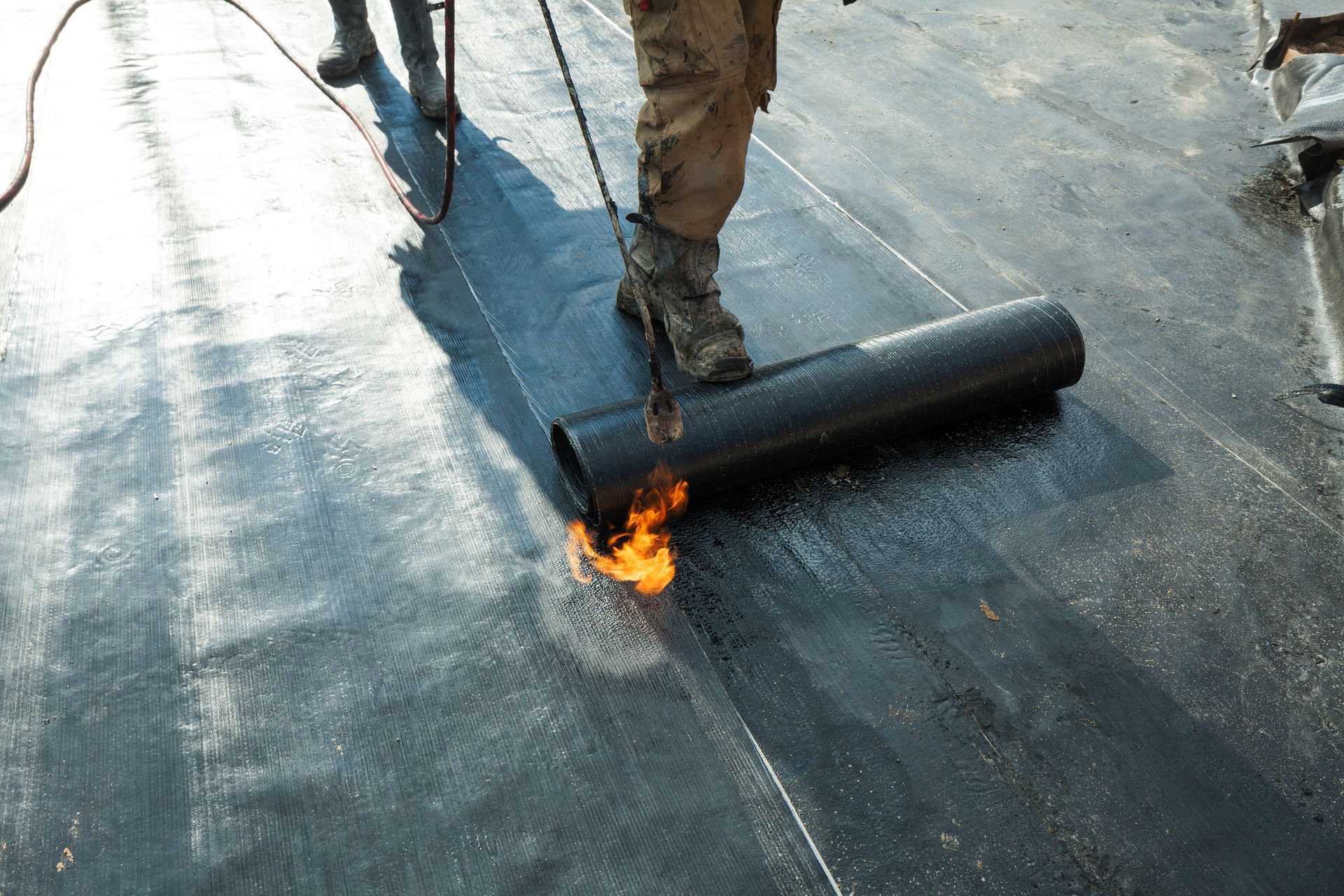 Two men installing a roof on a building, demonstrating teamwork in commercial roofing services.