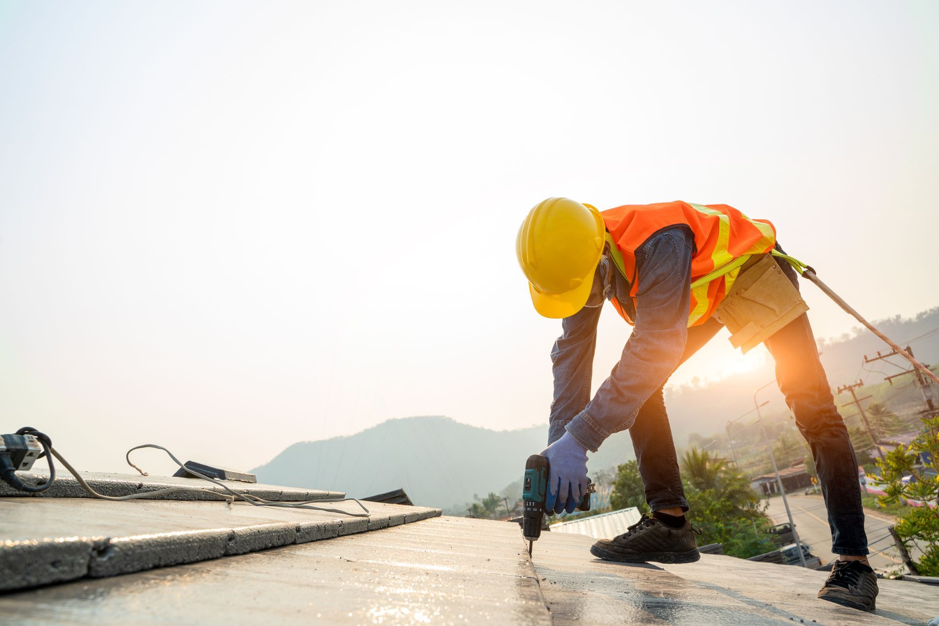 A man in a safety vest and hard hat is working on a roof, focusing on commercial roofing services.