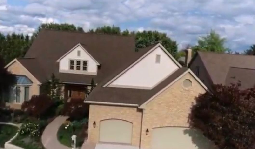 An aerial view of a large house with a brown roof