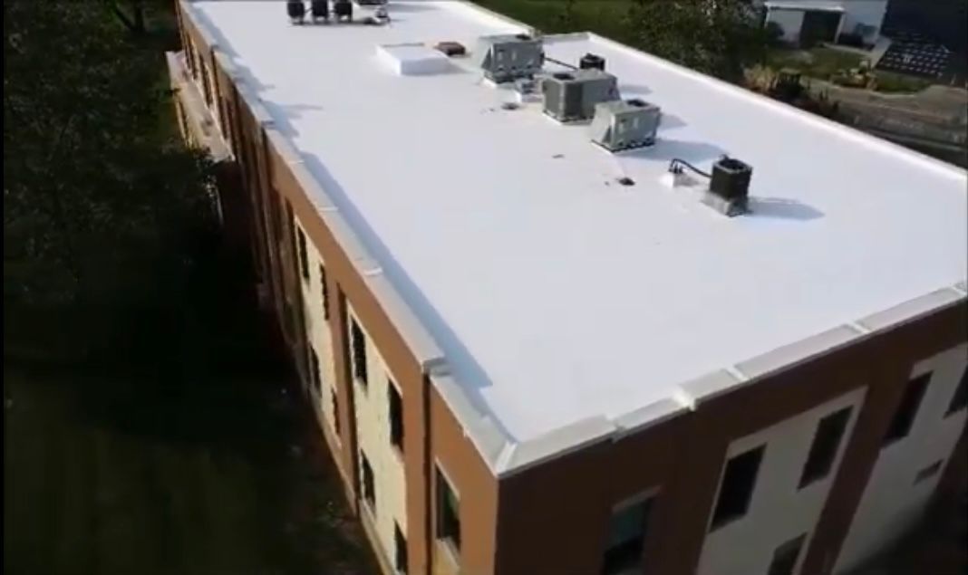 An aerial view of a large building with a white roof.