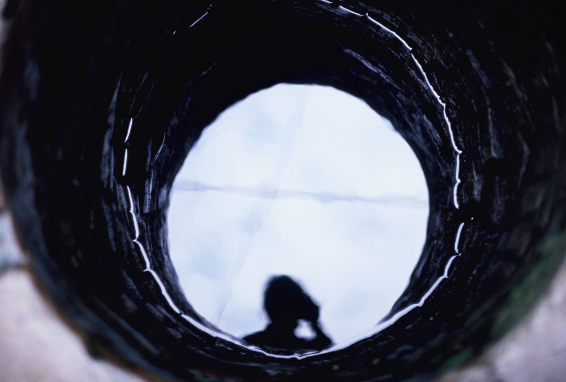 A reflection of a person on the water of a well.