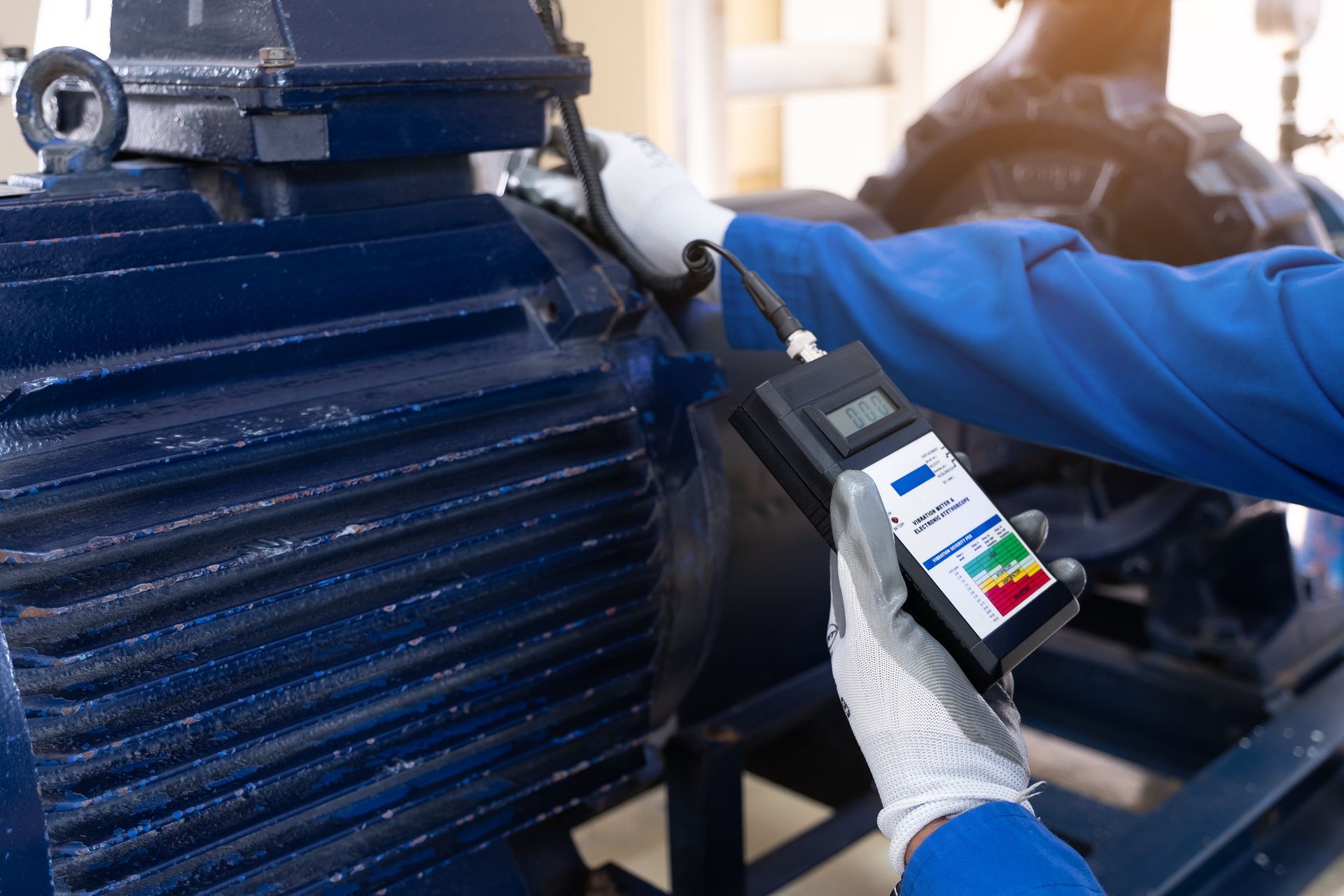 A man is holding a remote control in front of a motor.