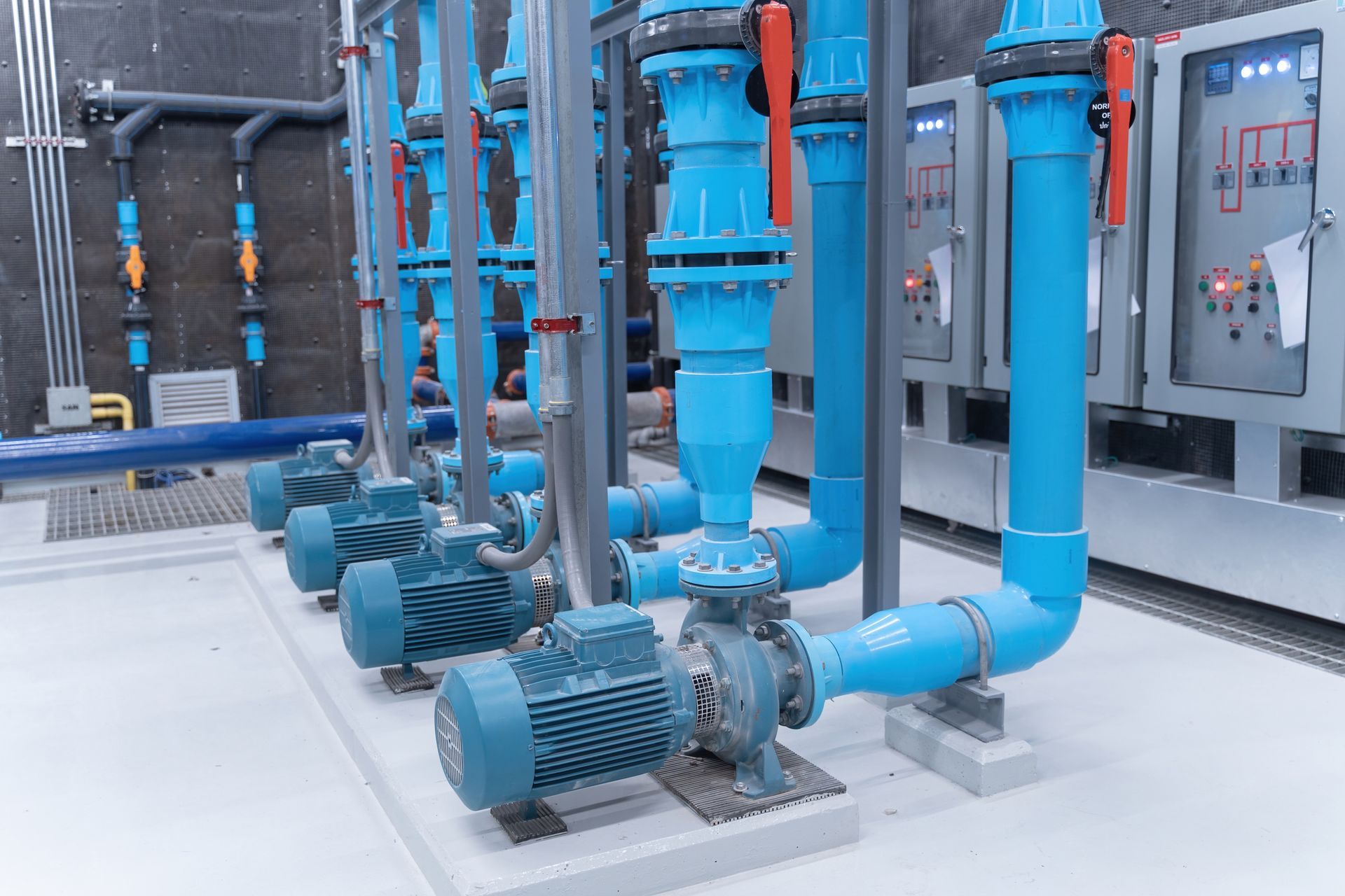 A row of blue pipes and pumps in a factory.