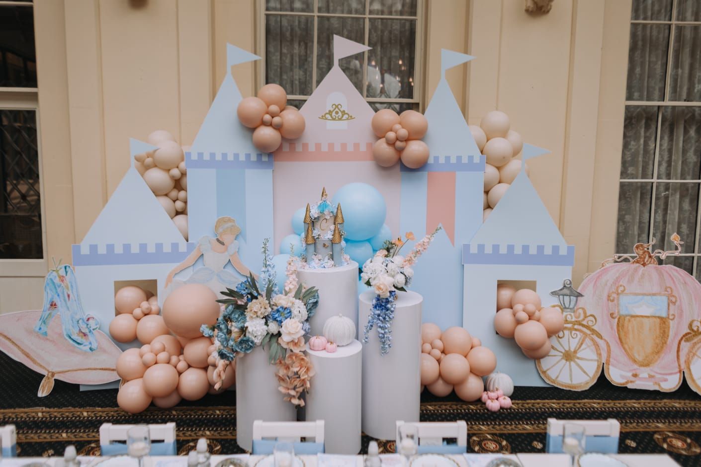 A cinderella themed birthday party with a castle backdrop and balloons.
