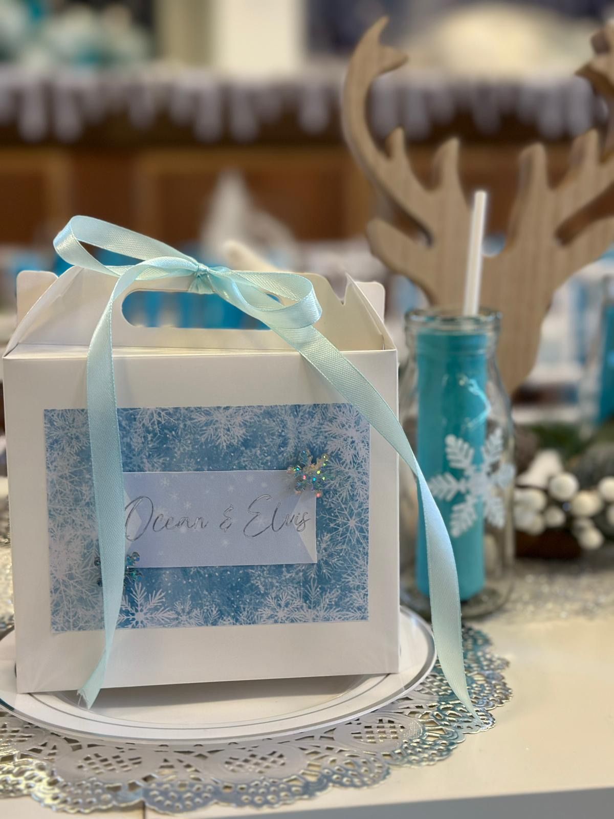 A white box with a blue ribbon is sitting on a plate on a table.
