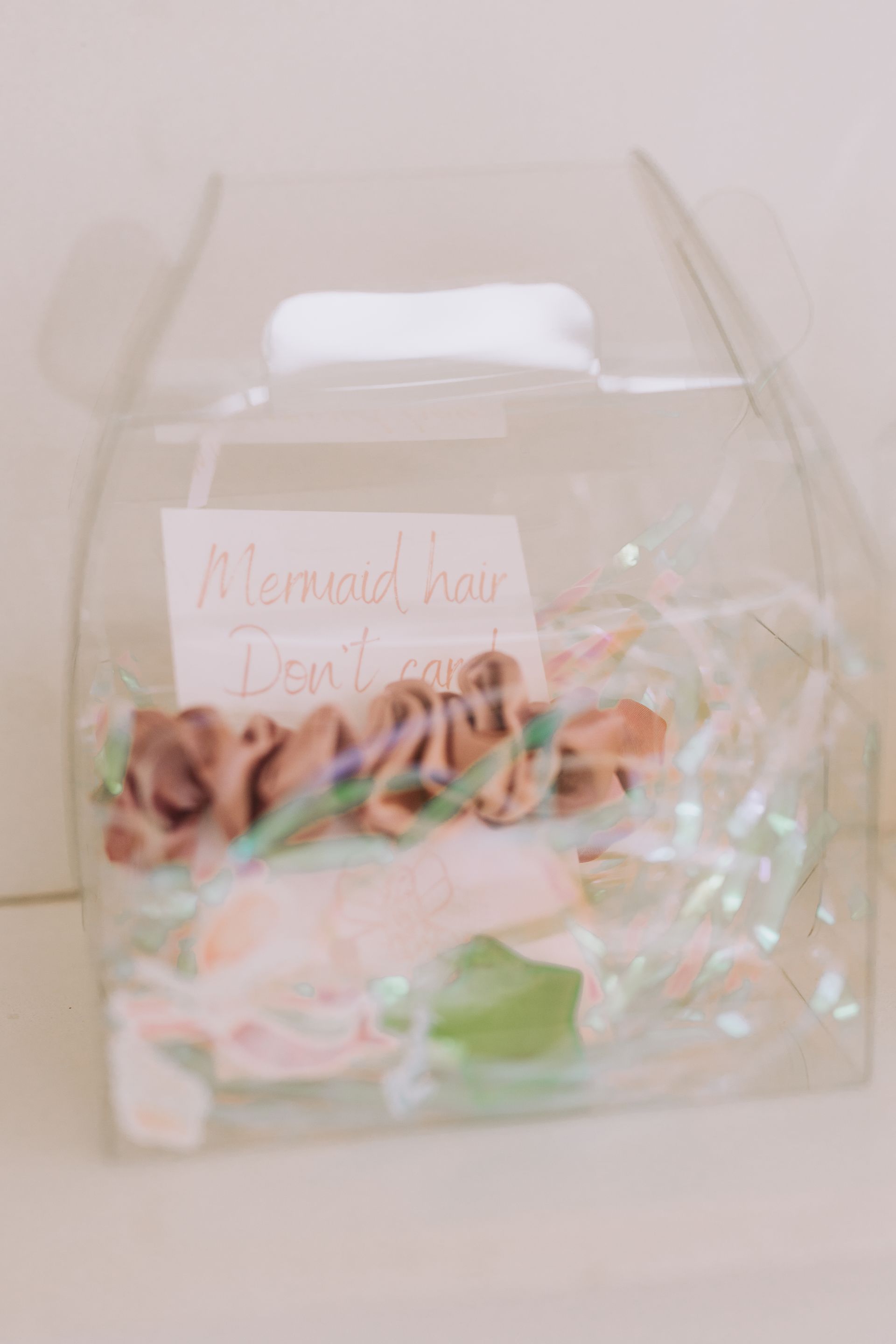 A clear plastic container filled with flowers and ribbons.