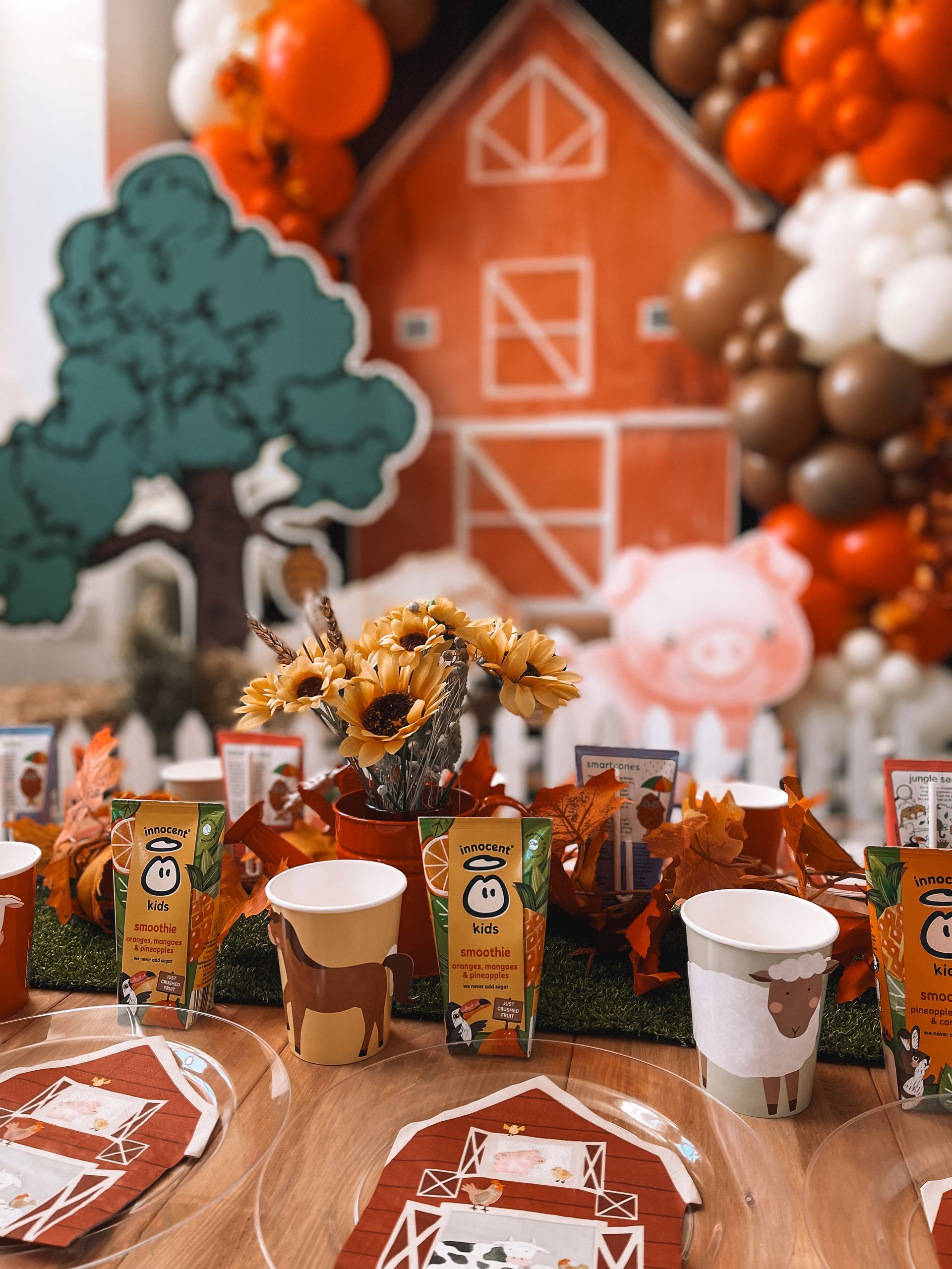 A table set up for a farm themed birthday party with plates , cups , napkins and balloons.