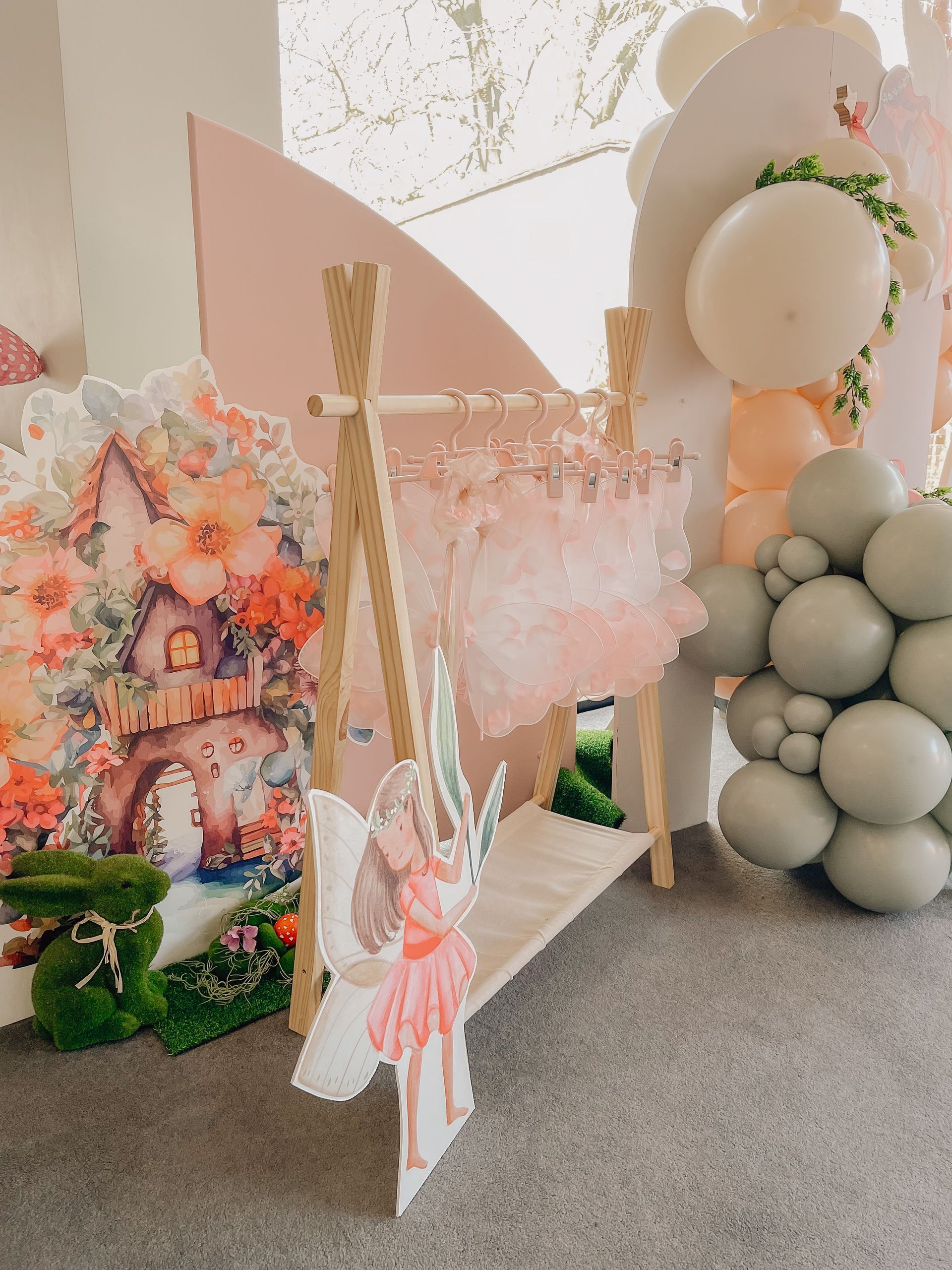 A fairy is sitting on a swing in a room with balloons.