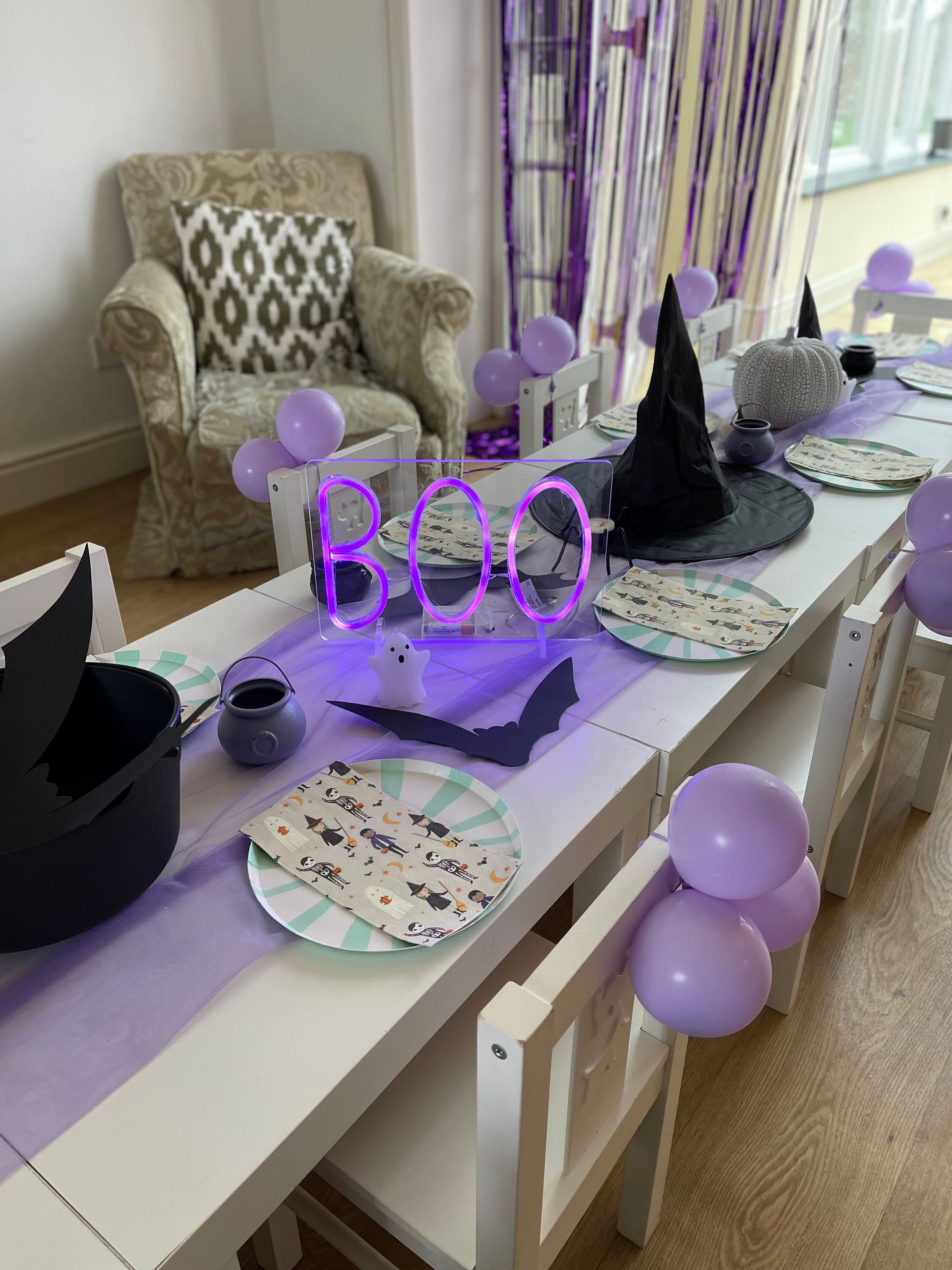 A long table with plates , balloons and a sign that says boo.