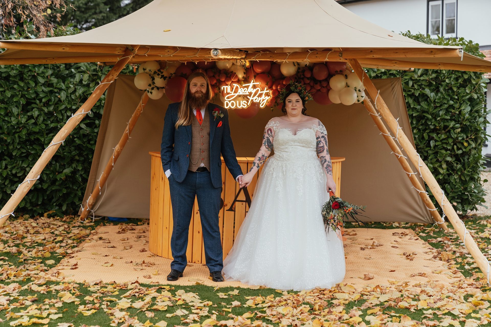 A bride and groom are standing under a tent holding hands.