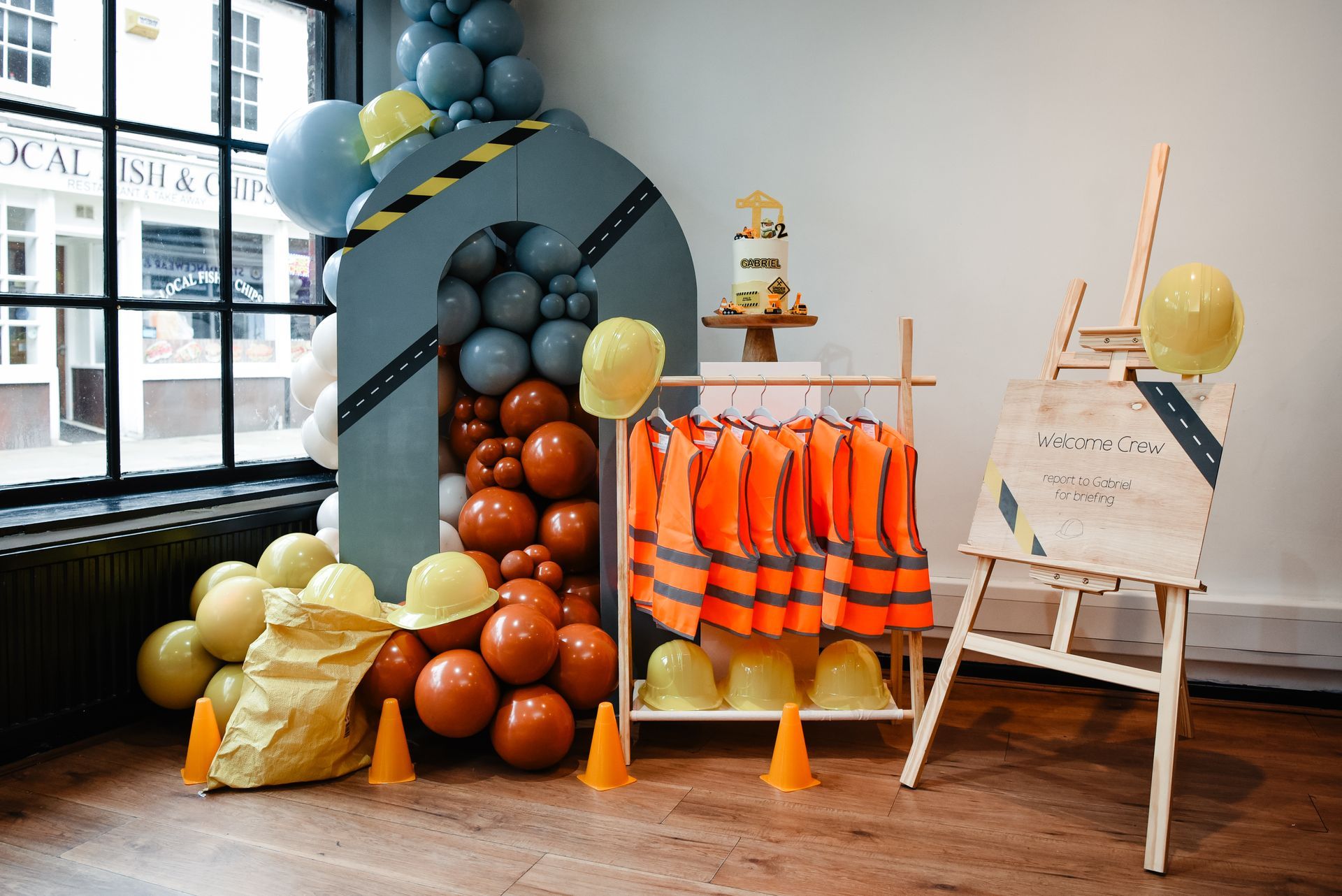 A room filled with balloons , hard hats , and safety vests.