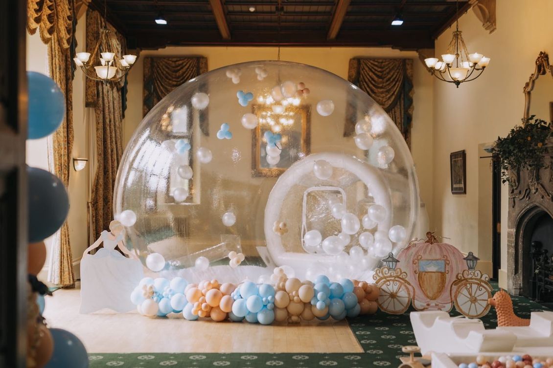 A large bubble filled with balloons in a room.