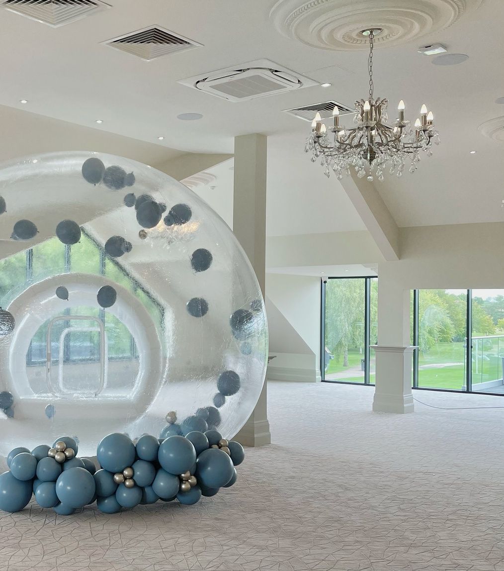 A large sphere filled with blue balloons in a room