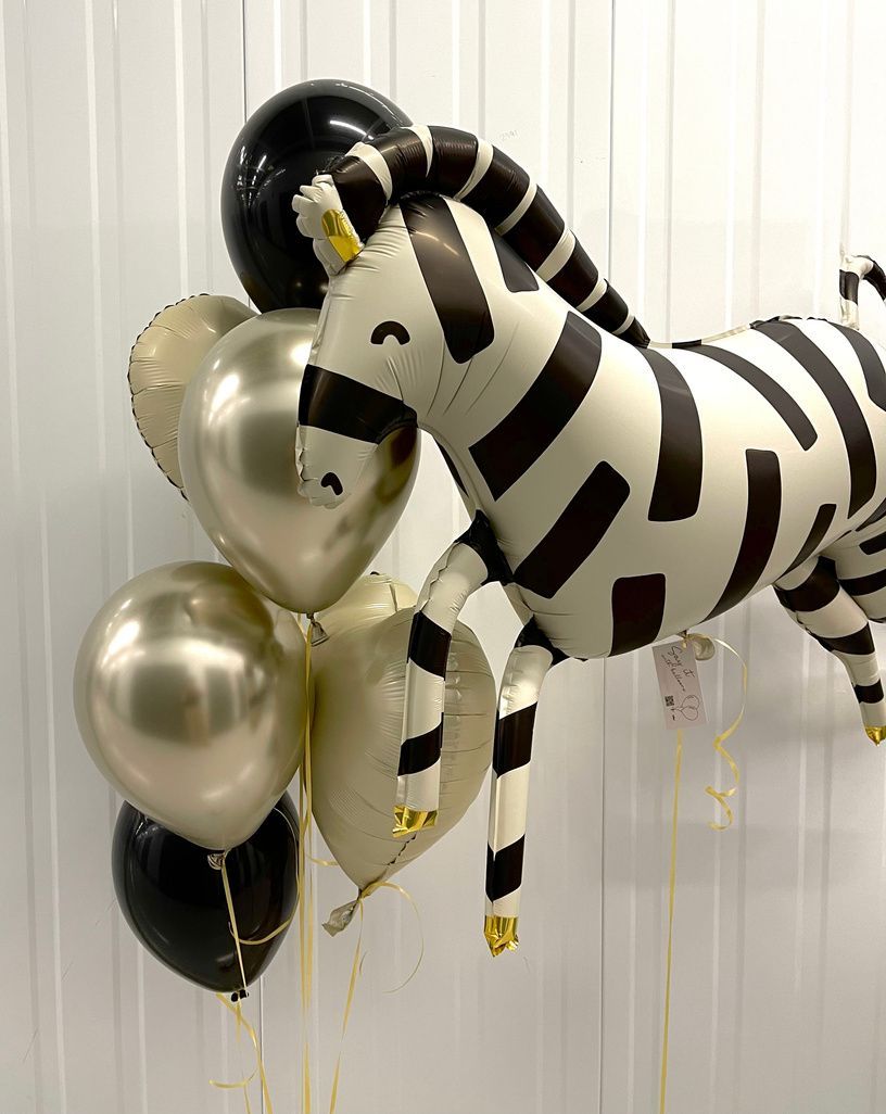 A black and white zebra balloon is surrounded by balloons