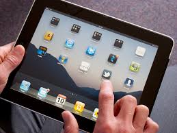 Picture of an iPad with a persons hand touching an app