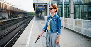 Blind woman waiting for a train at a train station with a cane.