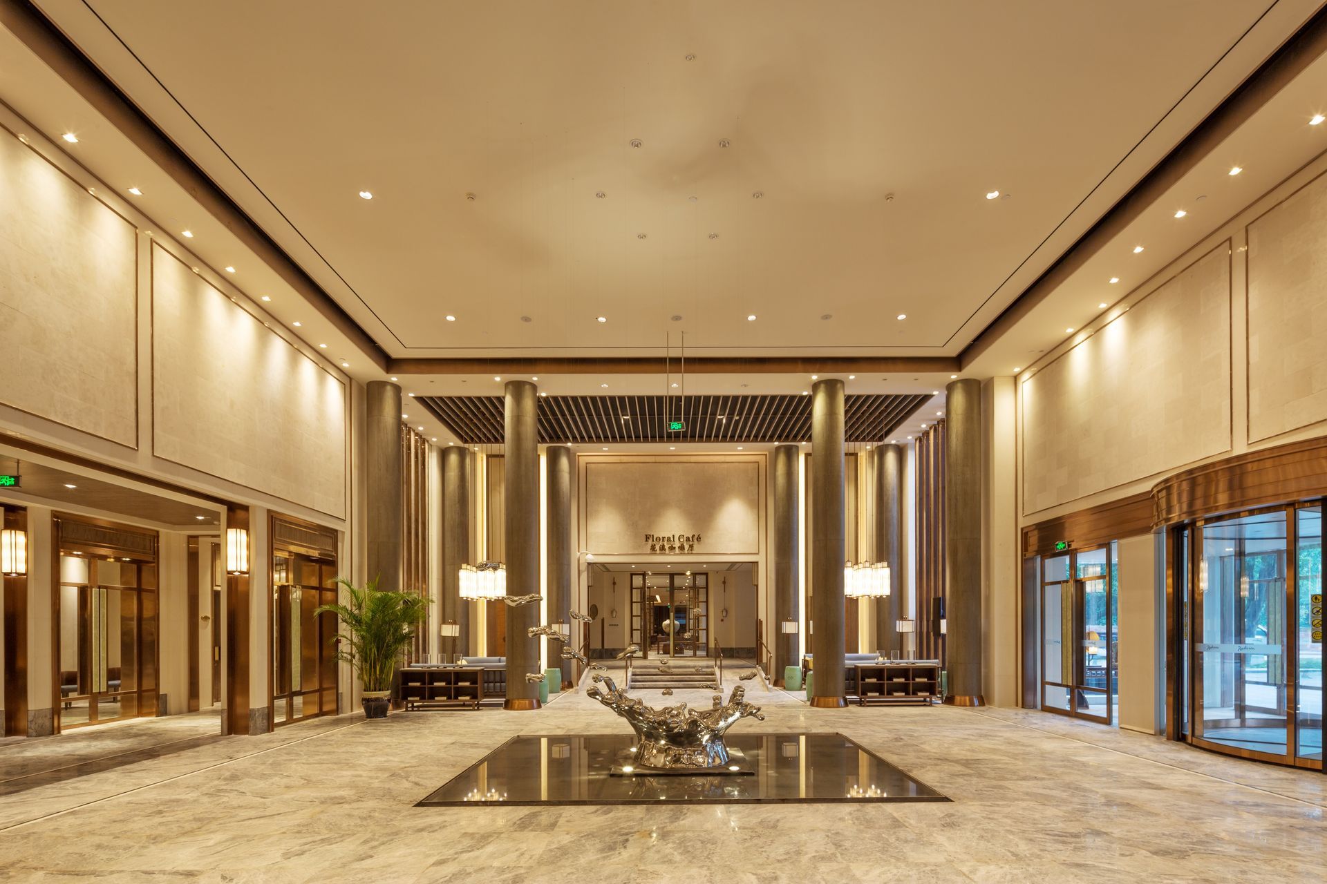 Elegant hotel lobby with marble floors, gold accents, and a central seating area under warm lighting