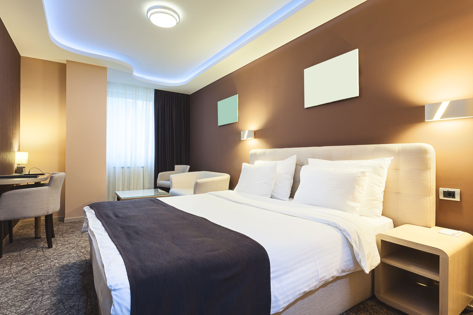 Modern hotel room with a large bed, dark accent wall, and soft lighting